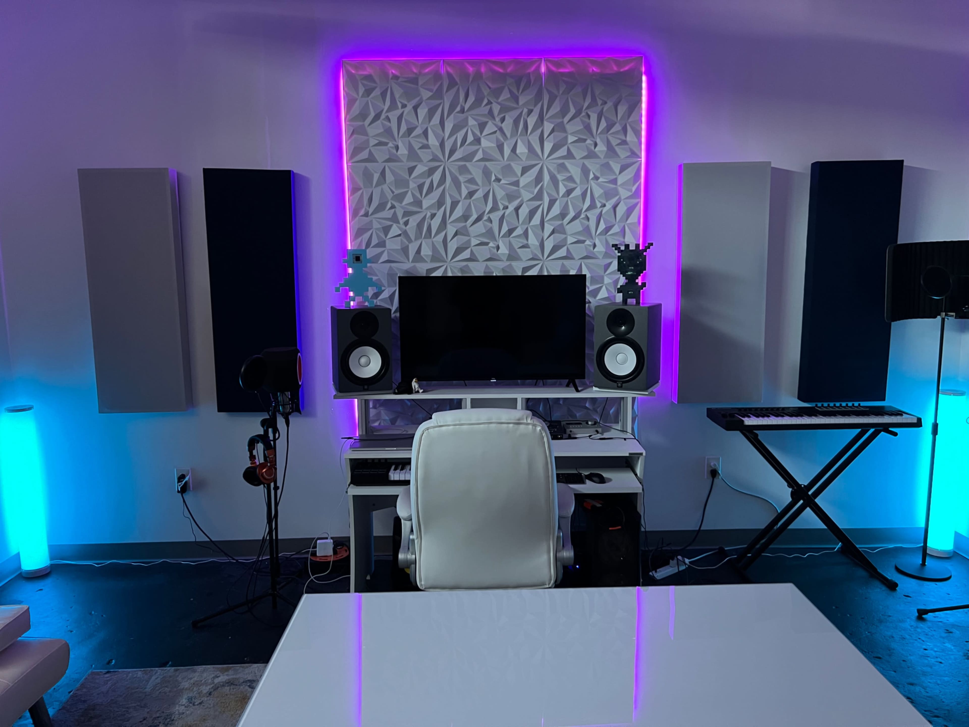 The image shows a modern home studio setup with a computer desk, speakers, and ambient lighting.