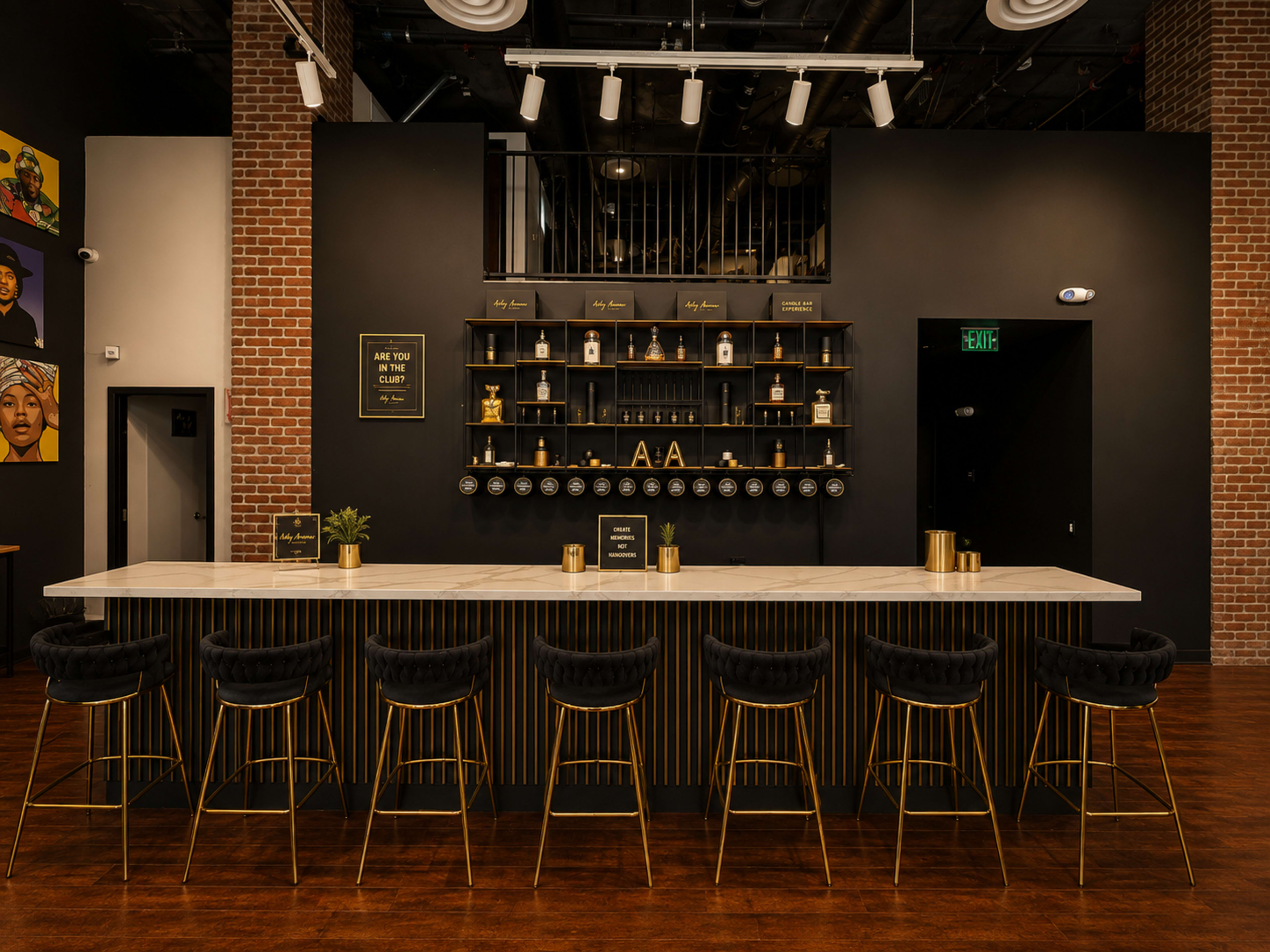 The image shows a modern bar area with a long marble countertop, black bar stools with gold legs, and a wall featuring shelves displaying various bottles and decorative items.