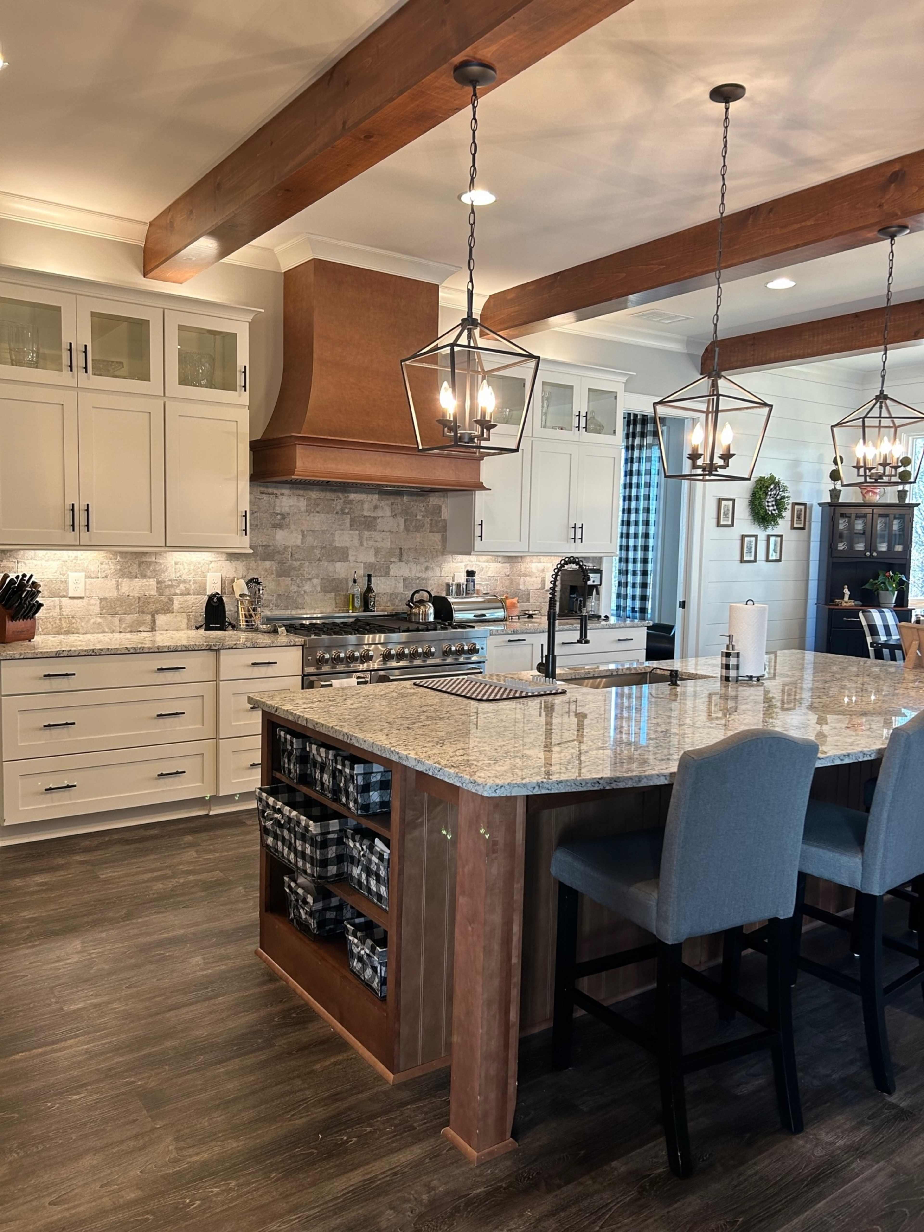 The kitchen features a central island with bar seating, light-colored cabinetry, a granite countertop, and pendant lighting above.
