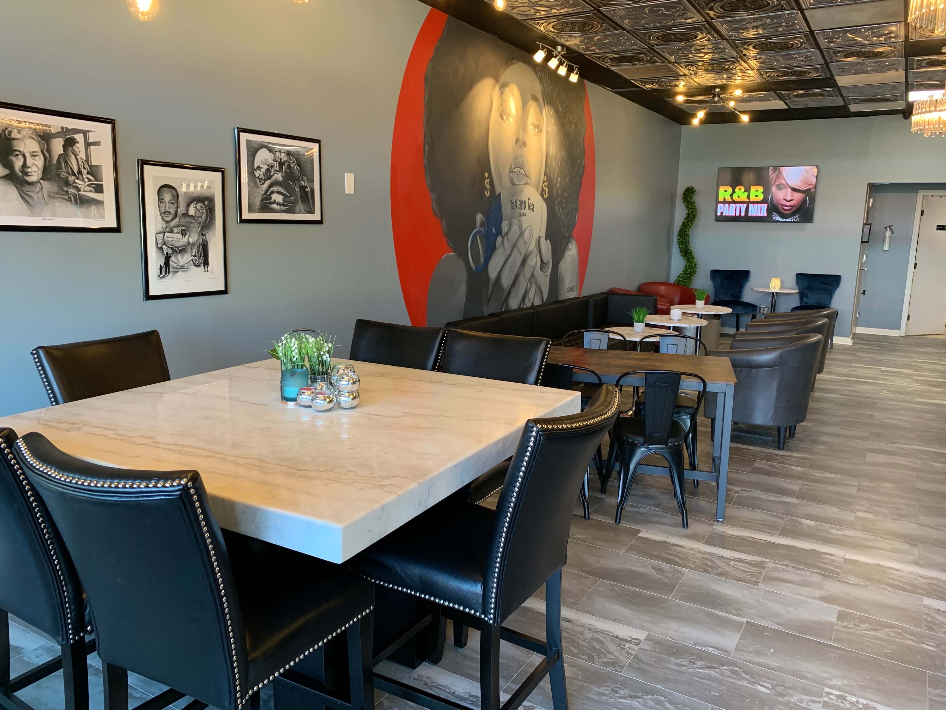 A modern lounge area featuring a large marble table, chairs, and colorful wall art in a well-lit setting.