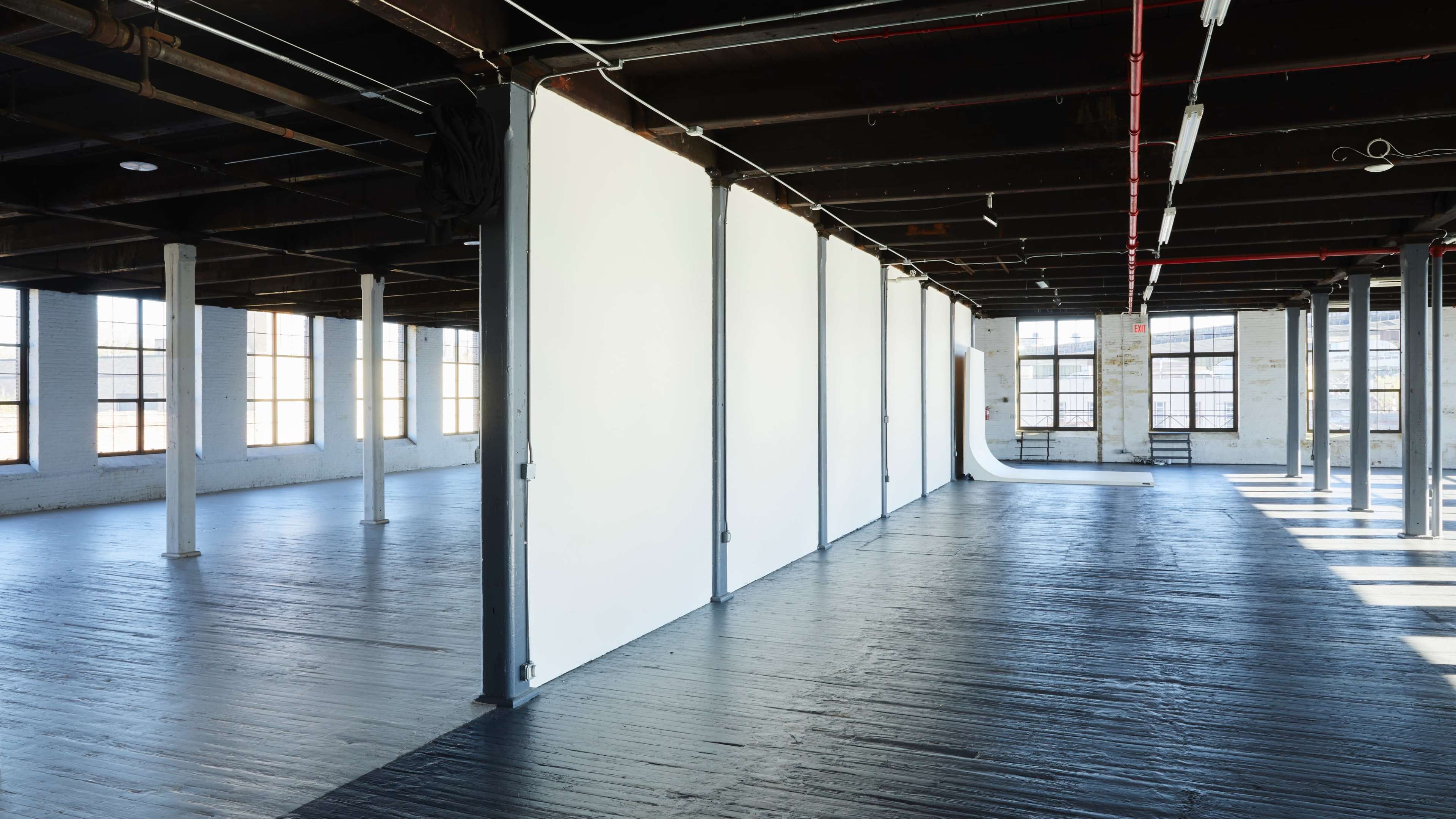 A spacious, industrial-style interior with large windows and white partition walls dividing the space.