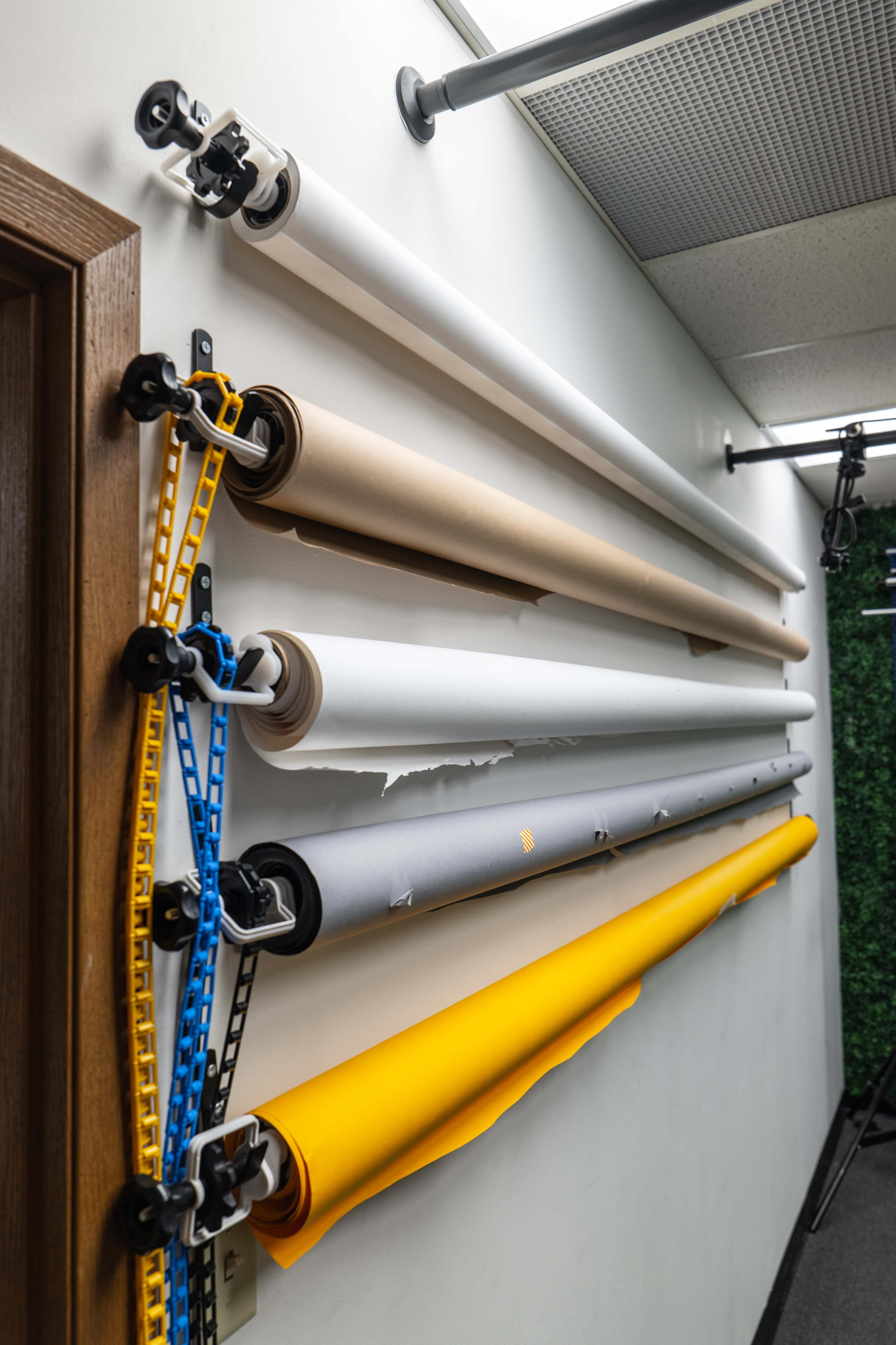 Rolls of colored backdrop paper are organized on a wall-mounted rack.