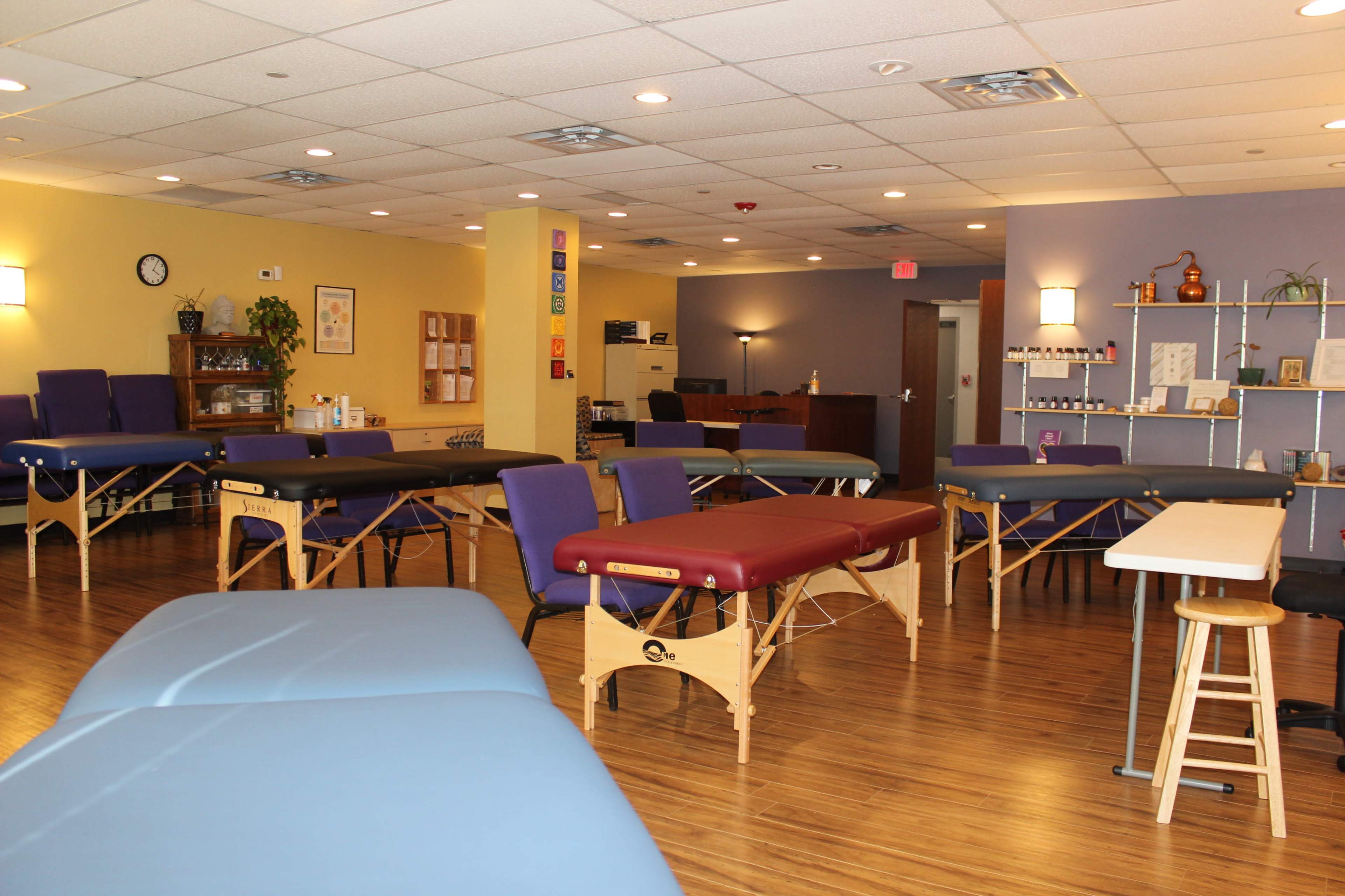 A spacious therapy room with multiple treatment tables arranged in a neatly organized layout and soft ambient lighting.