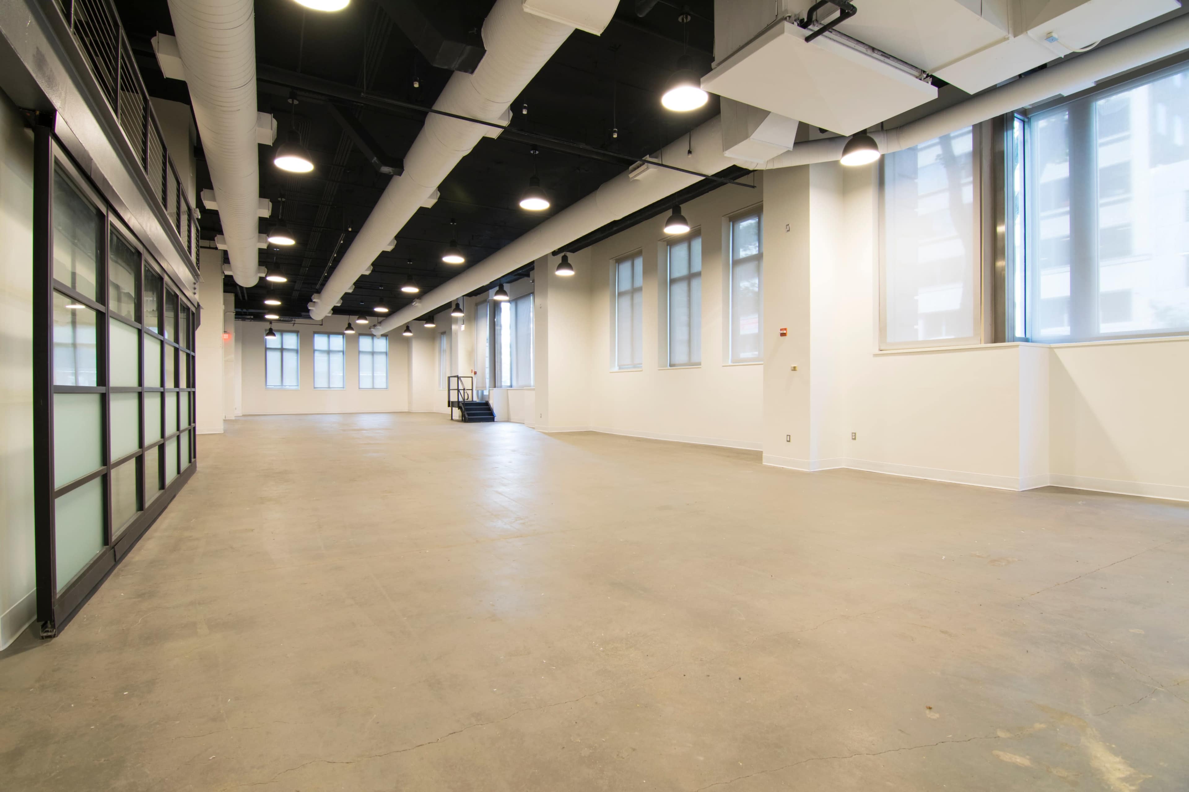 A spacious, empty room with large windows and a polished concrete floor.