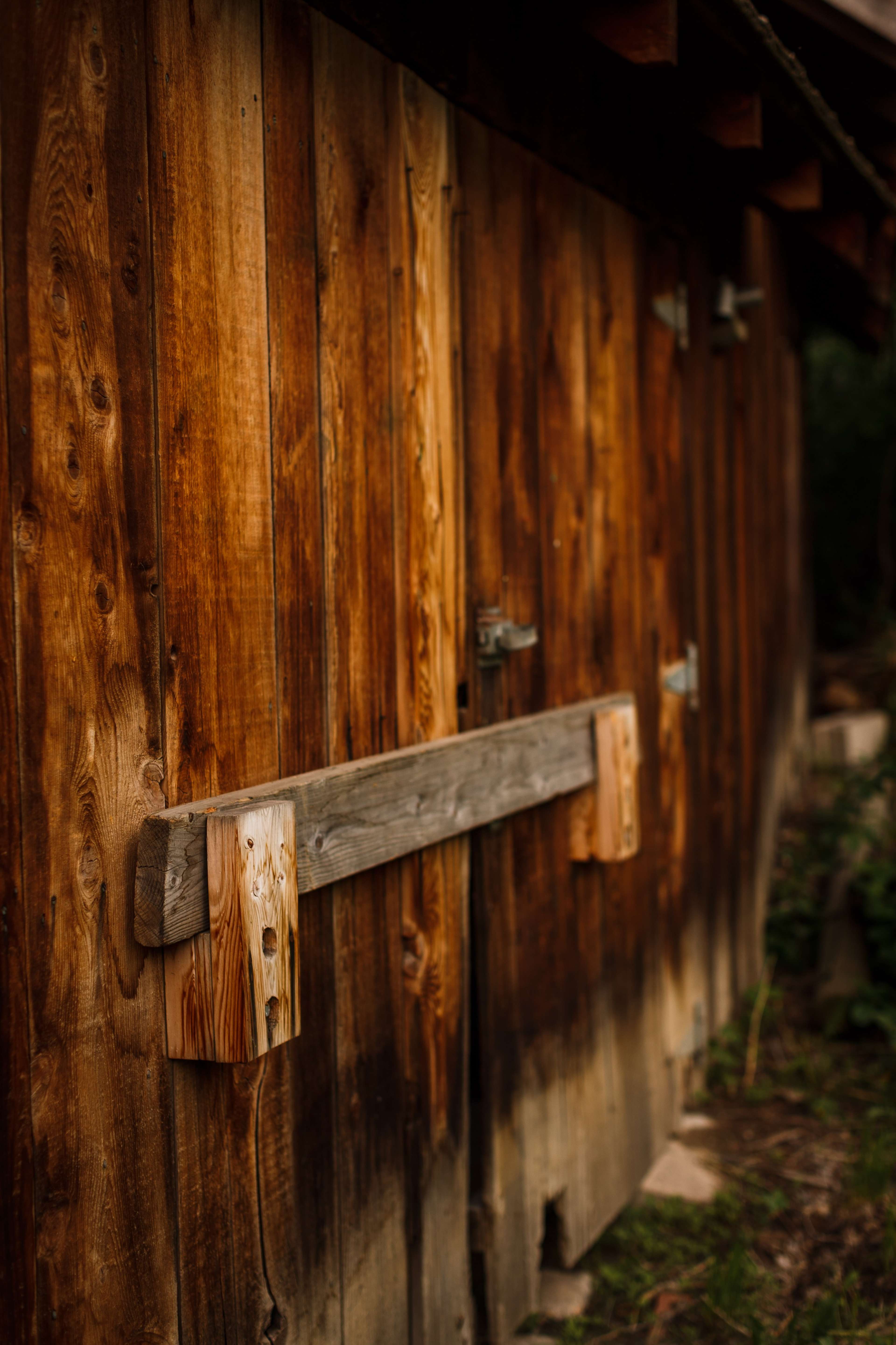 A wooden barn with large, sturdy doors and a rustic latch fixed to the center.