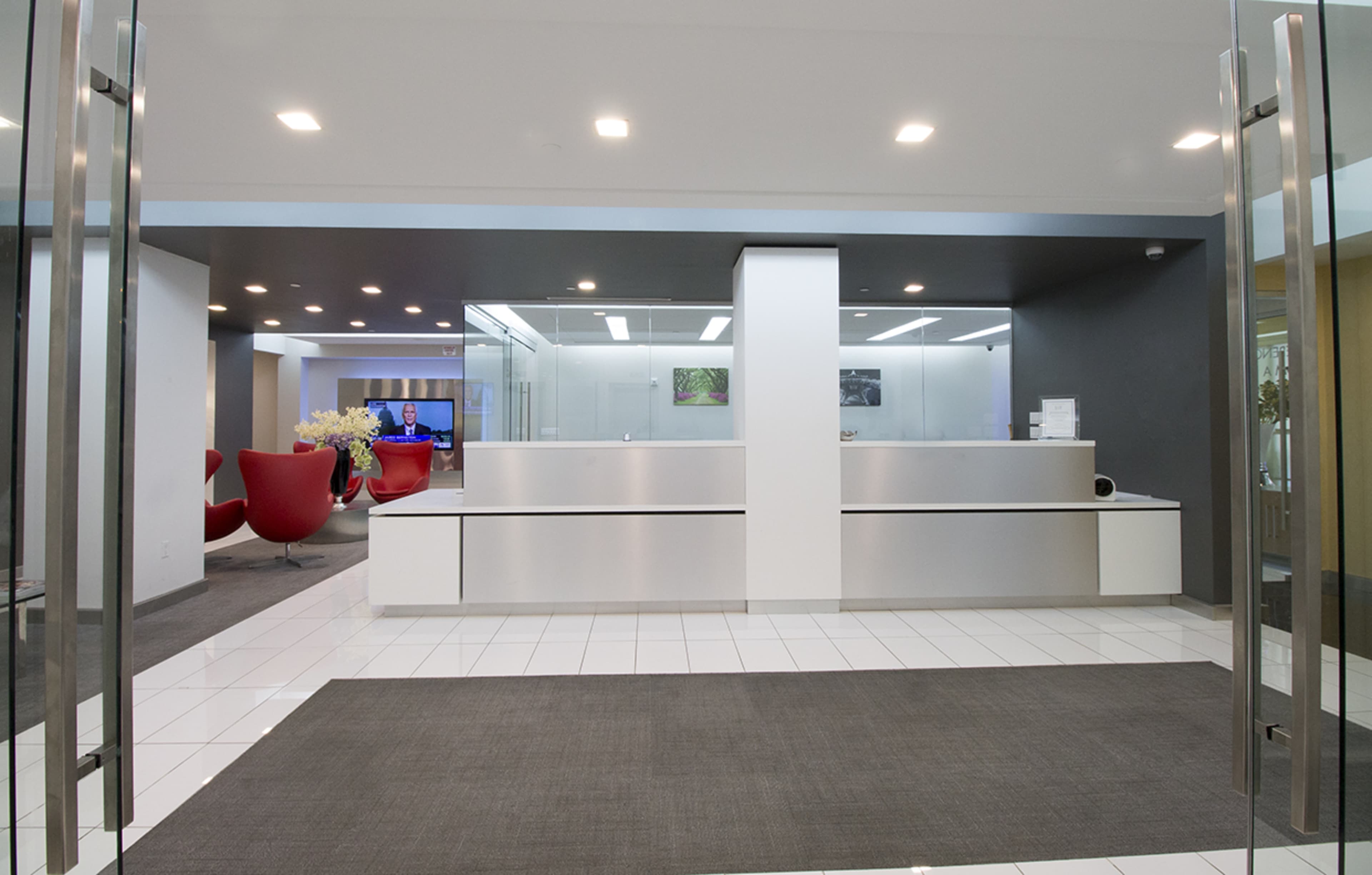 A modern reception area with a sleek front desk, large glass doors, and comfortable seating in the background.