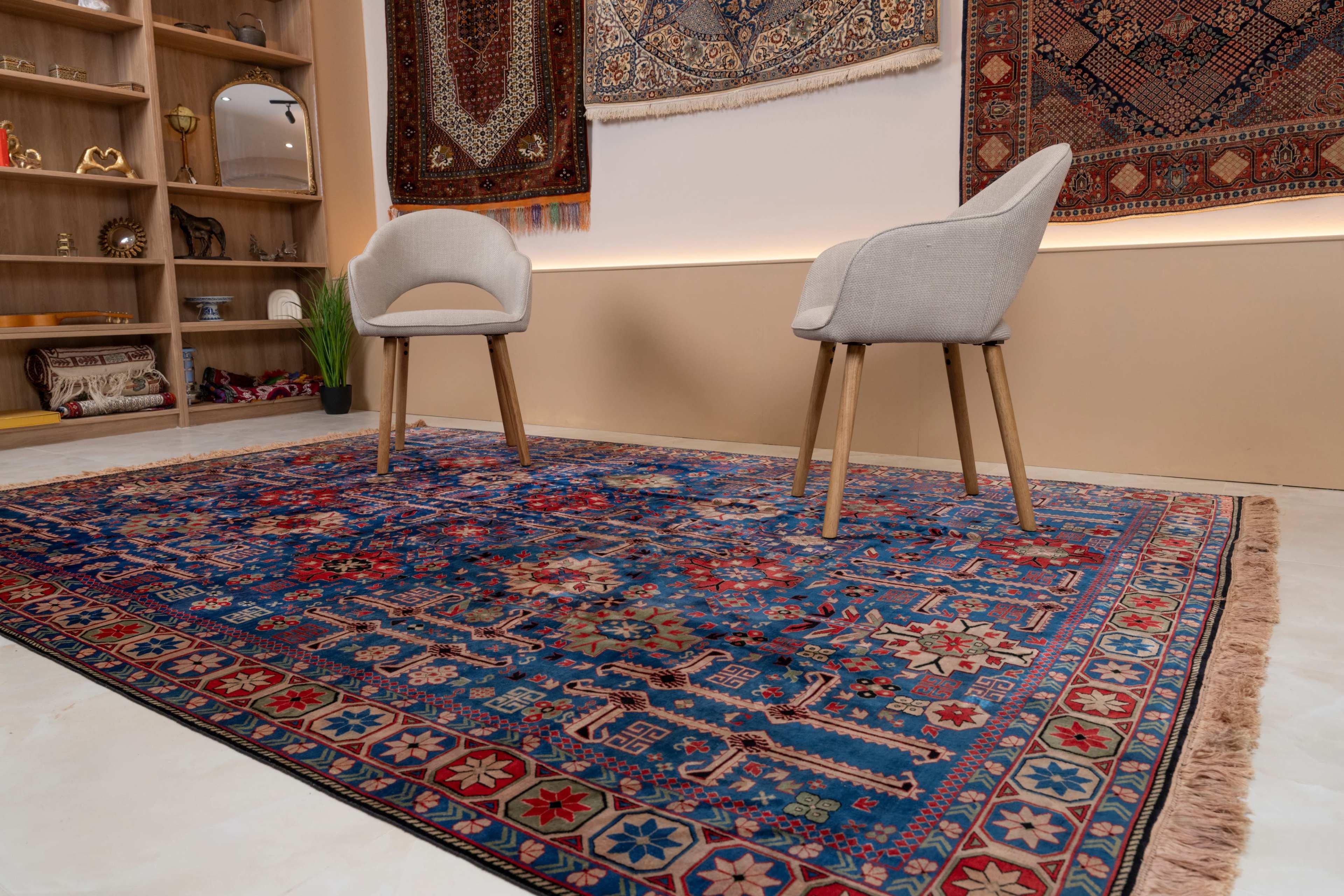 The image shows a cozy room with two modern chairs placed on a vibrant Persian rug, against a backdrop of decorative wall hangings.