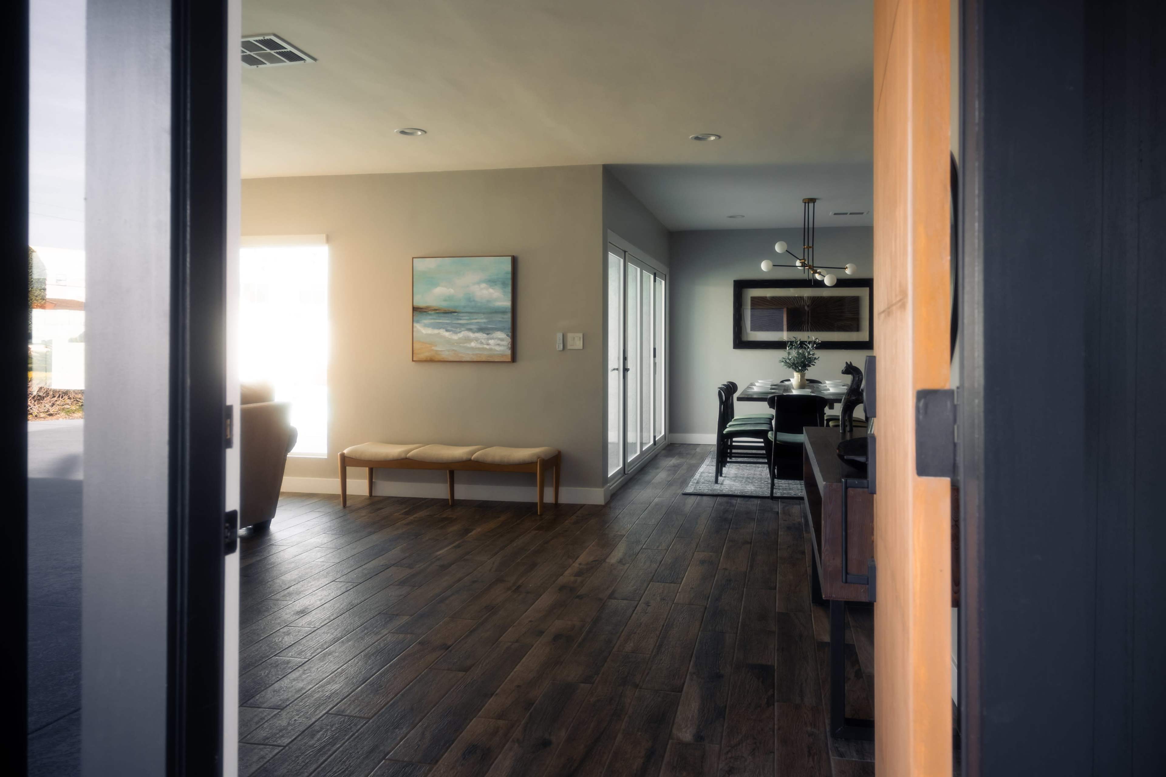 A modern entryway leading into a light-filled living space with wooden flooring and contemporary decor.