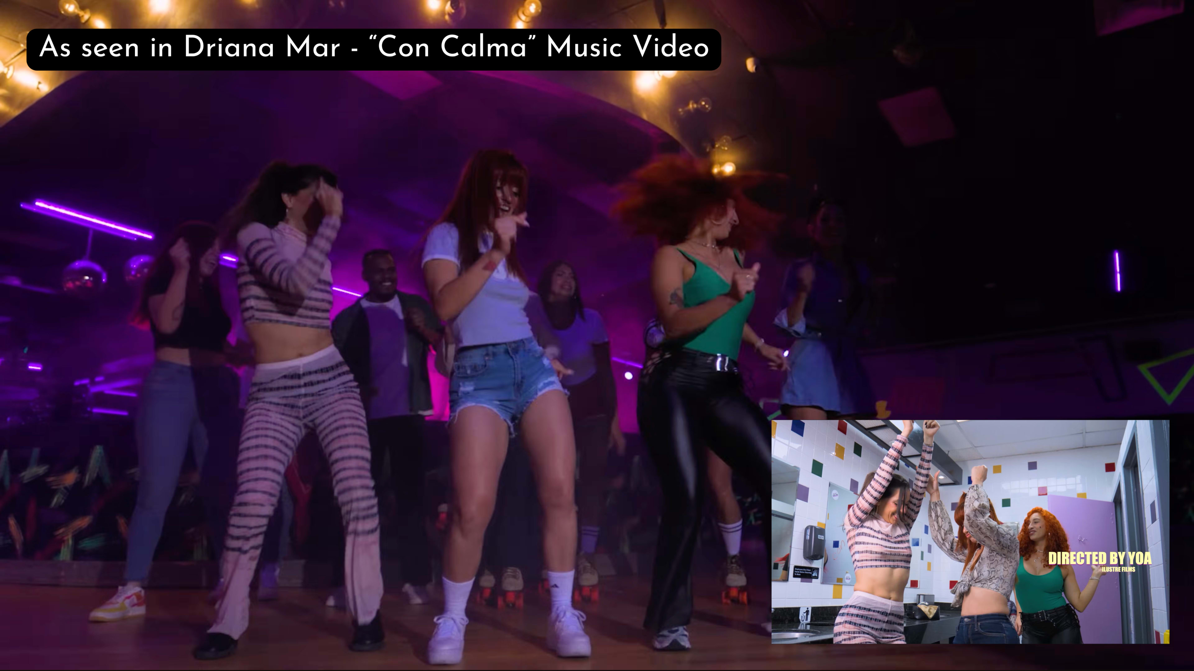 The image showcases a vibrant dance scene from the music video "Con Calma," featuring a group of performers dancing energetically under colorful lights.