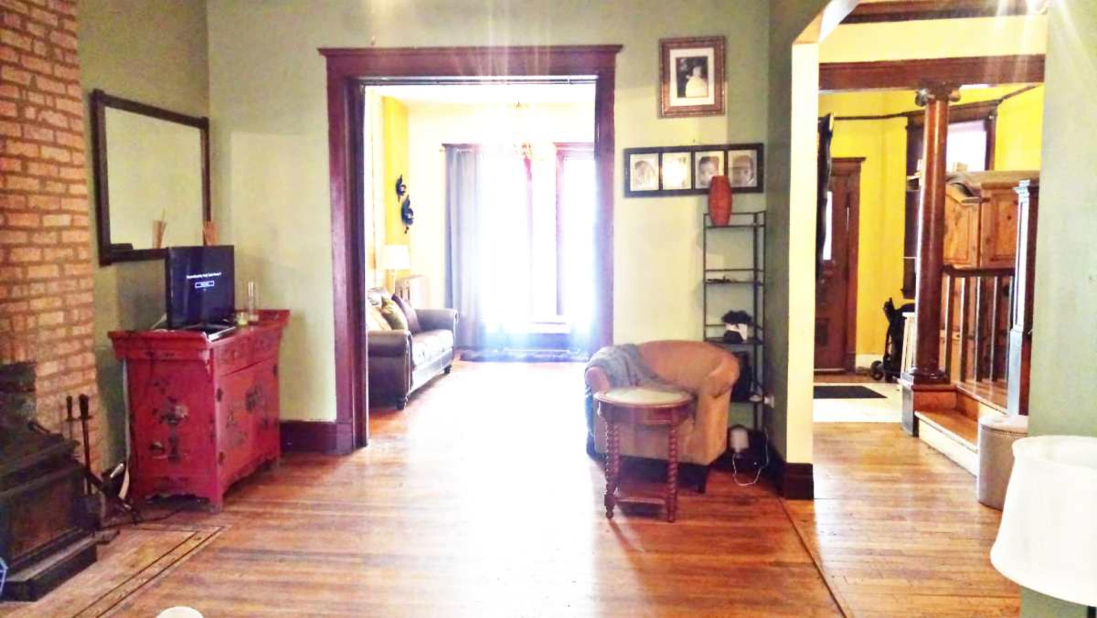 The image shows a living space with wooden floors, a red cabinet, a television, and doorways leading to other rooms.