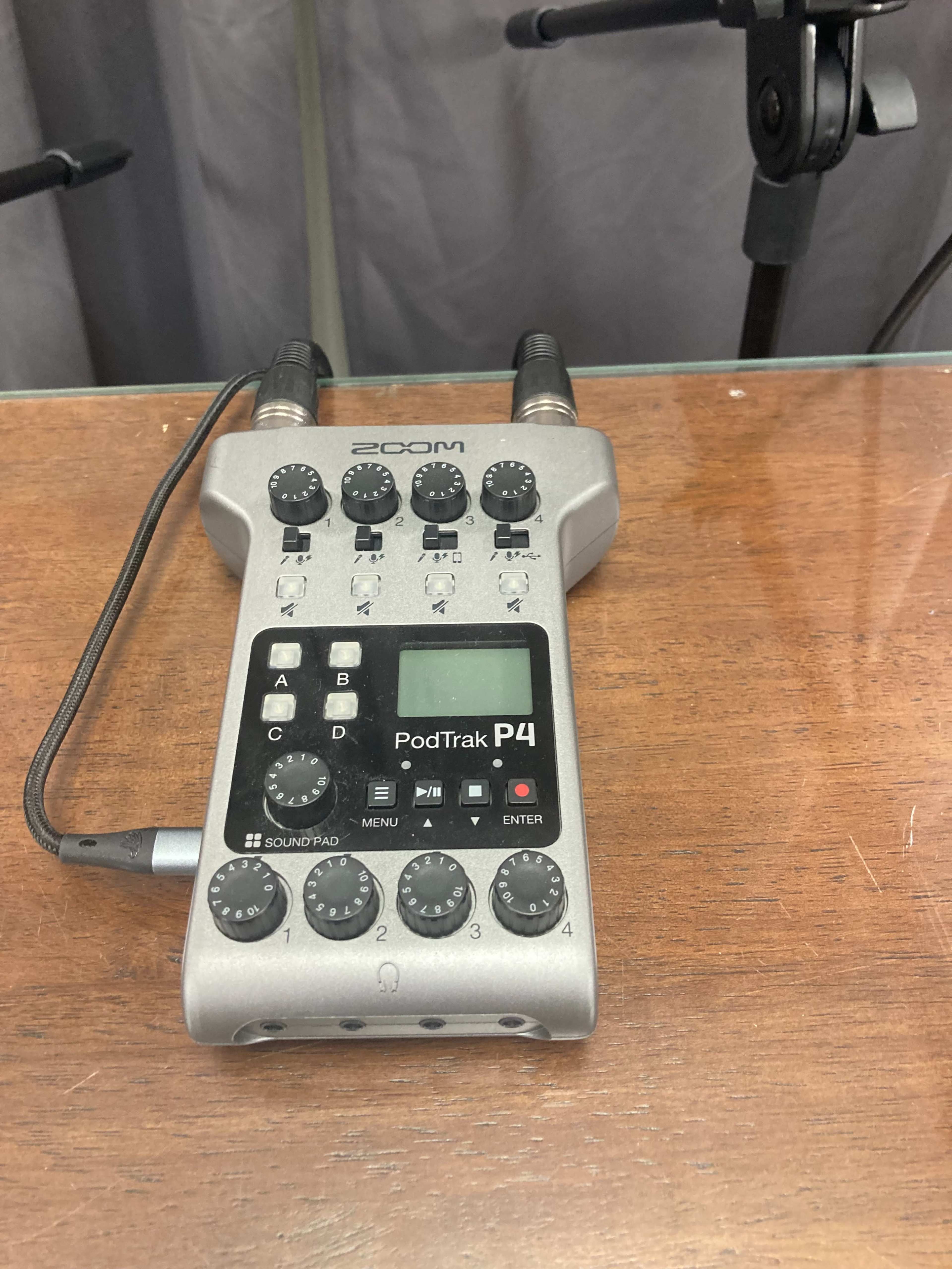 A Zoom PodTrak P4 audio recorder placed on a wooden surface.