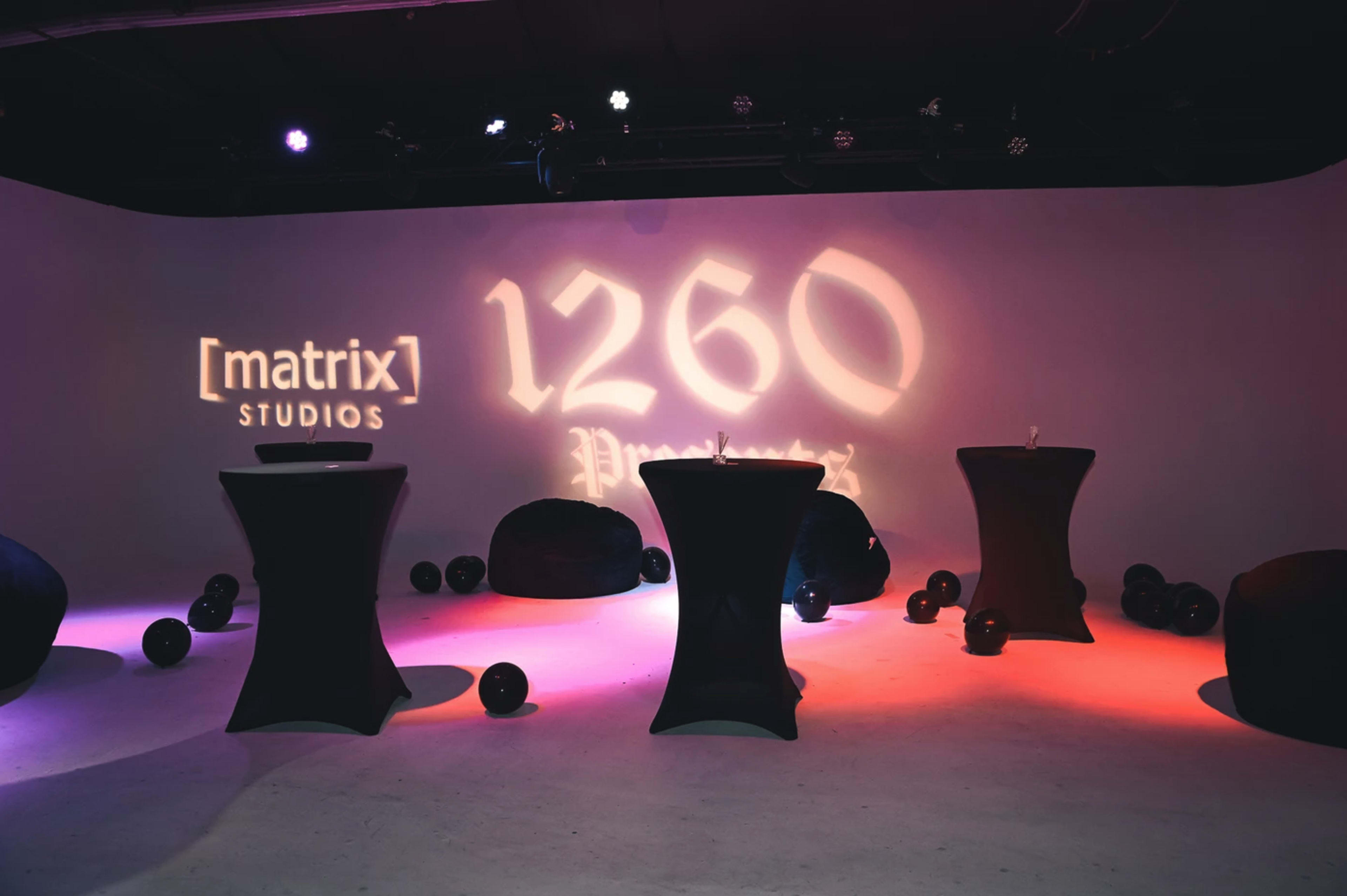 The image shows a modern event space with four tall black tables and a soft-lit background featuring the text "[matrix] STUDIOS 1260 Presents."