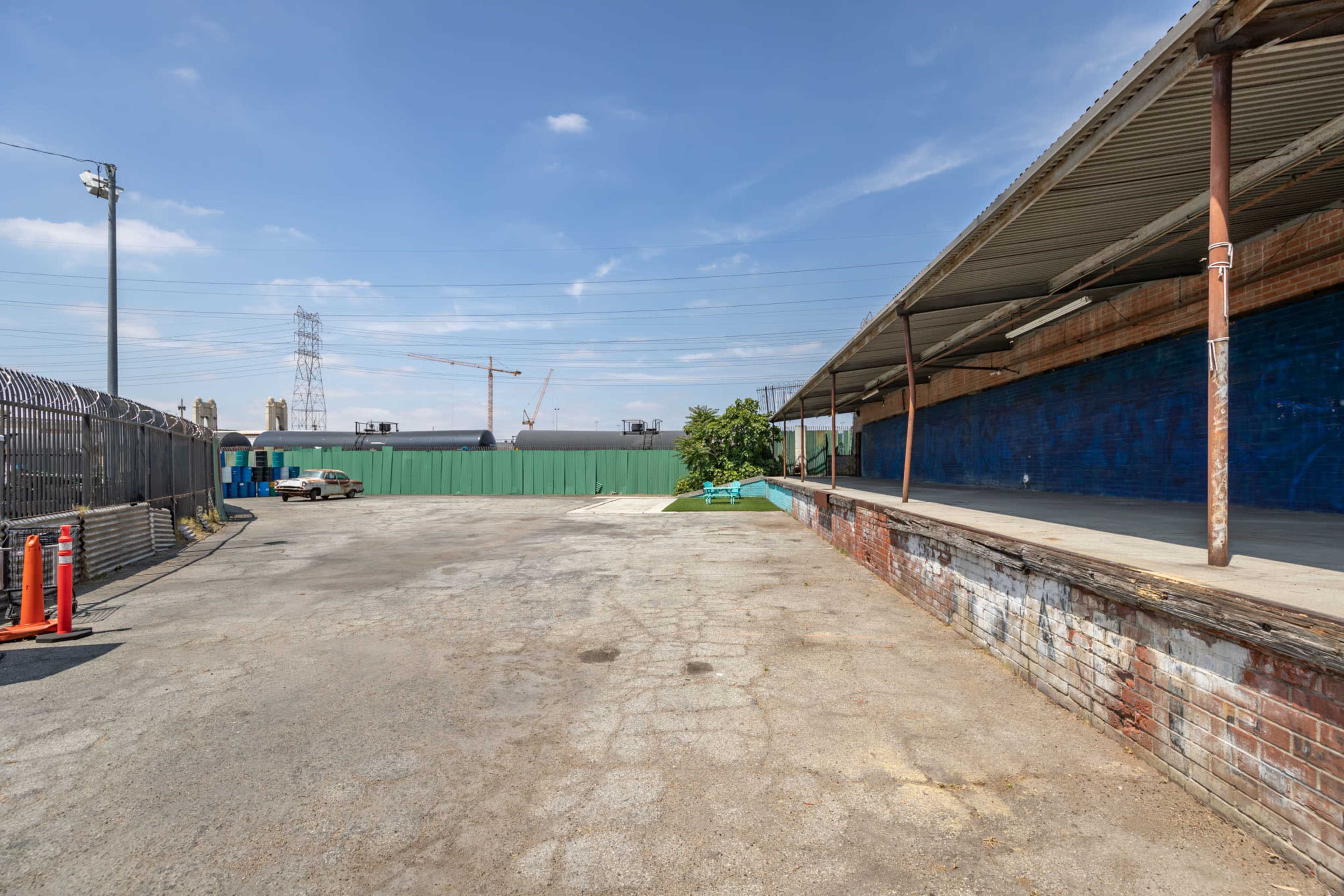 The image shows a vacant industrial area with a concrete surface, a covered loading dock, and a green storage container in the background.