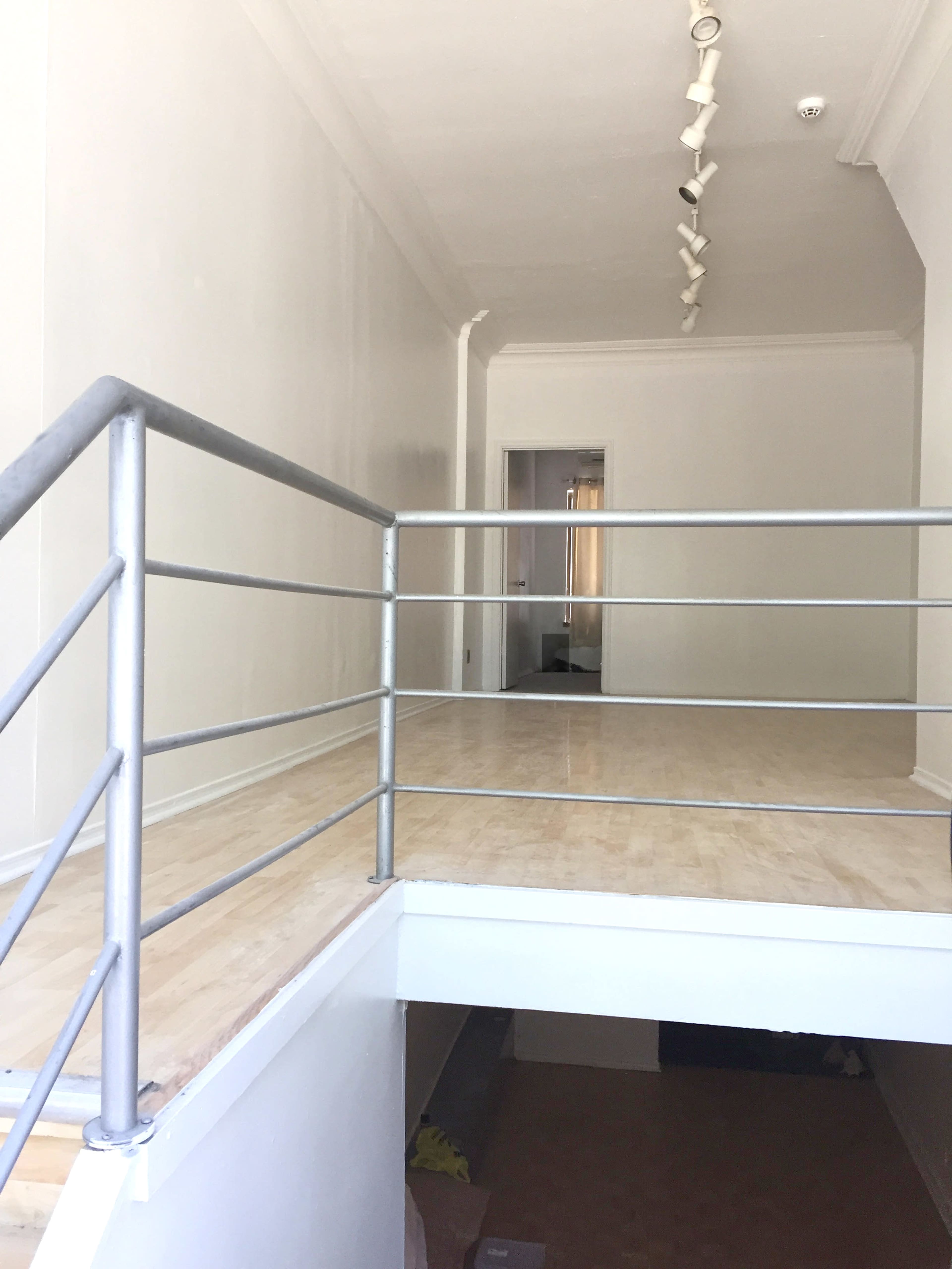 A staircase with a metal railing leads to a second-level open space in a light-colored room.