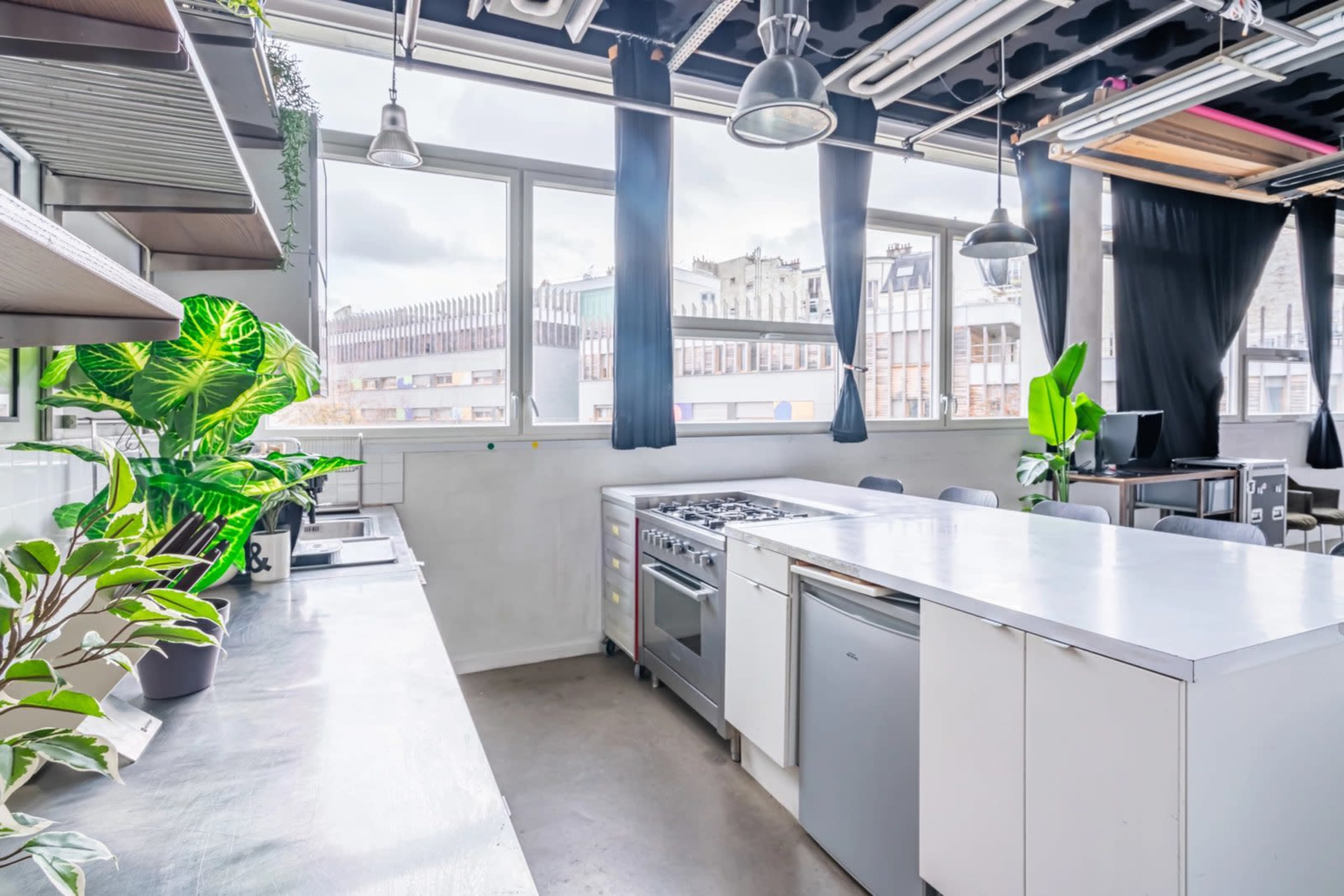 A modern kitchen features a large island, stainless steel appliances, and ample natural light from a large window.