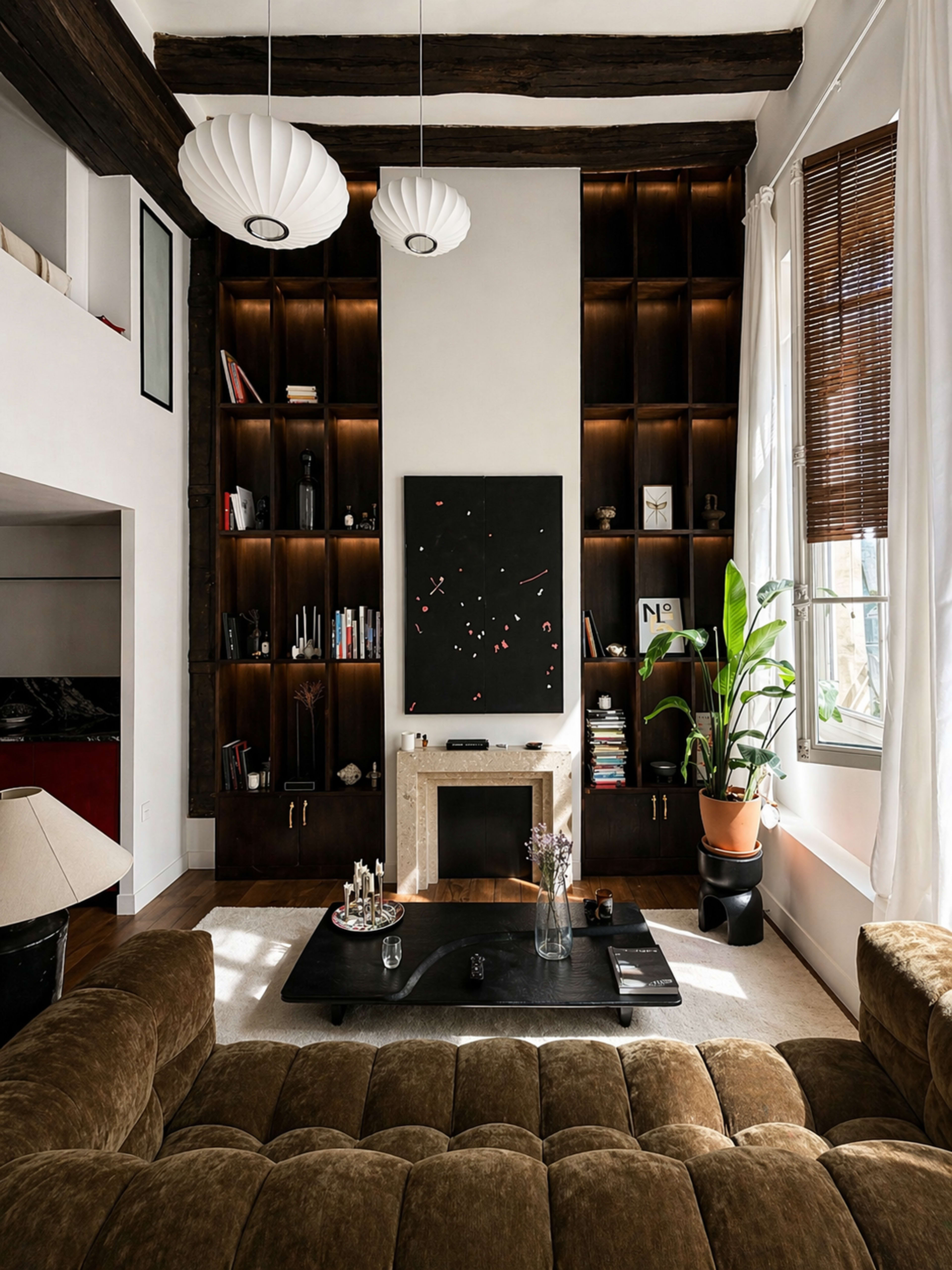 The image shows a modern living room featuring a brown tufted sofa, a black coffee table, a minimalist art piece, and tall bookshelves filled with books and decor.