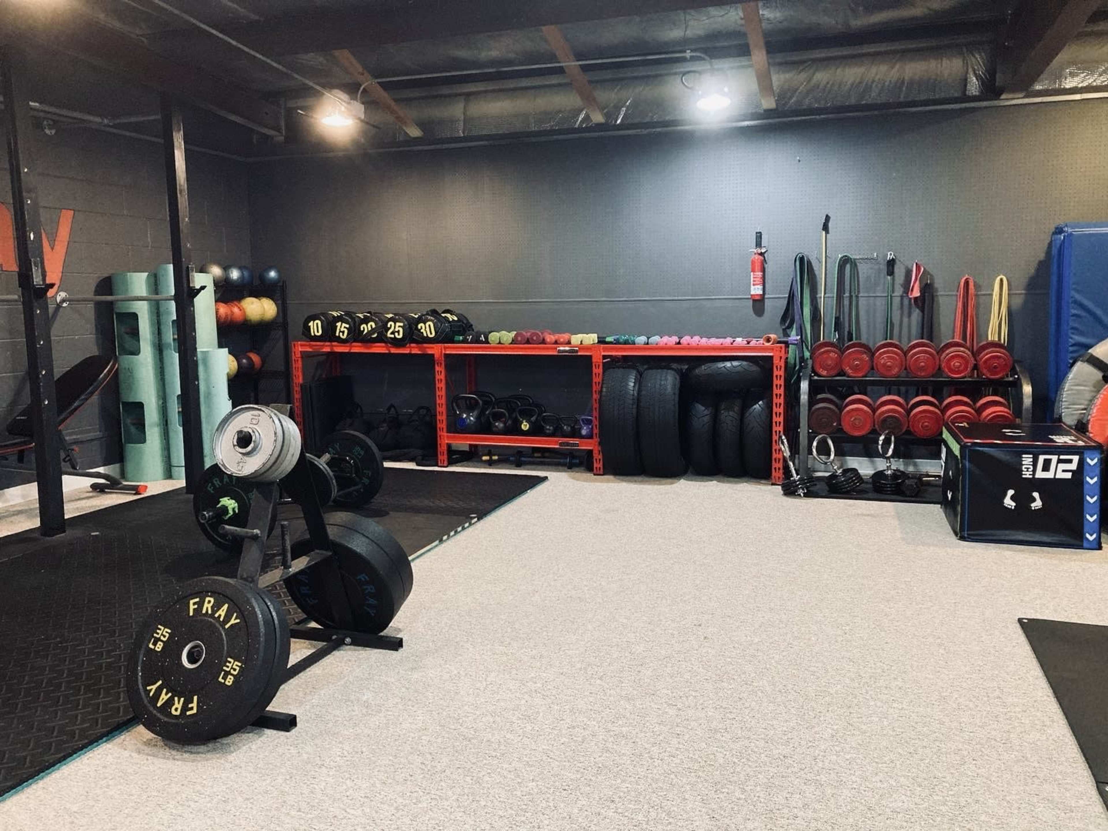 A gym interior featuring various weights, exercise equipment, and storage shelves filled with gym accessories.