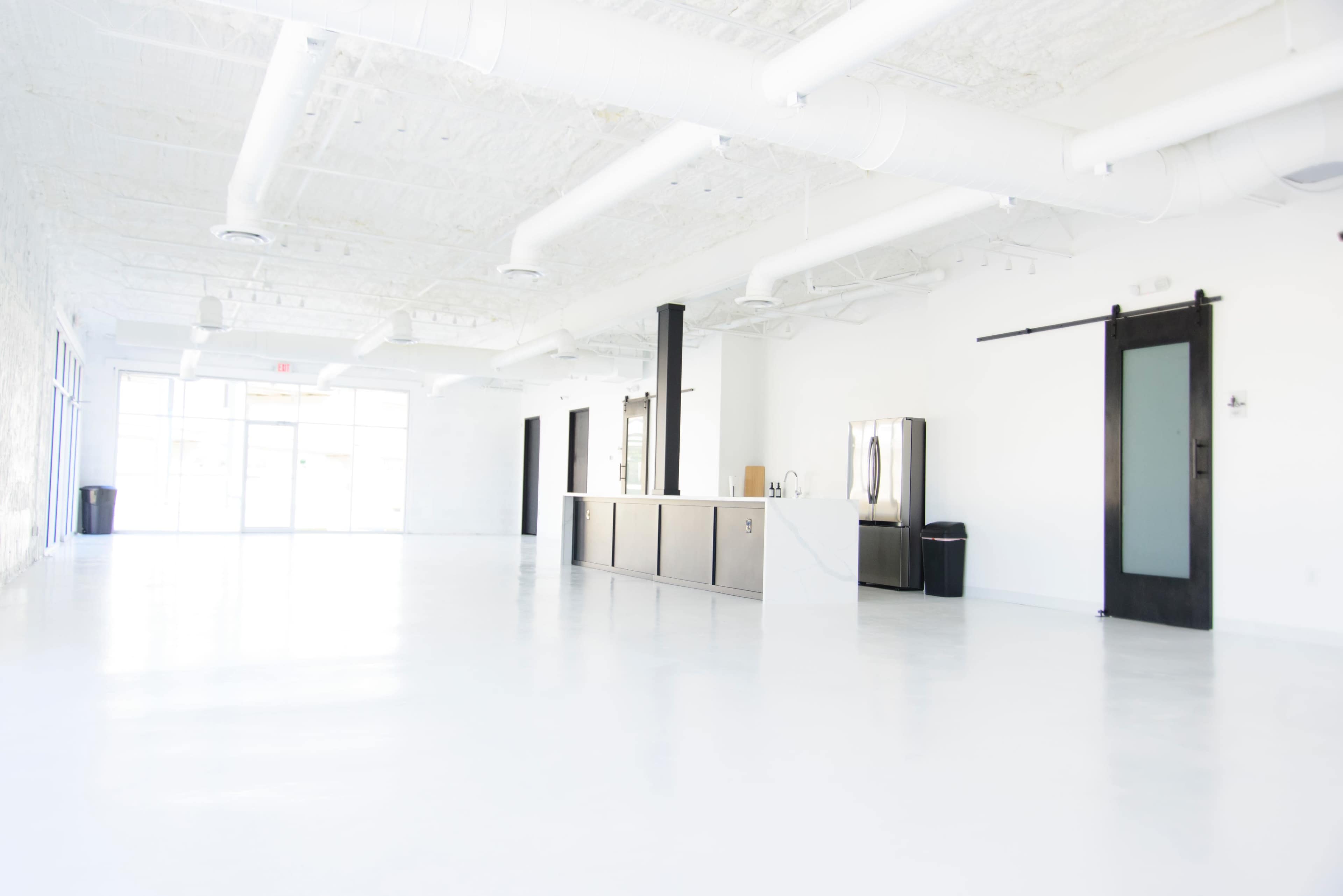 A spacious, well-lit interior with a sleek counter and minimal furniture against a white backdrop.