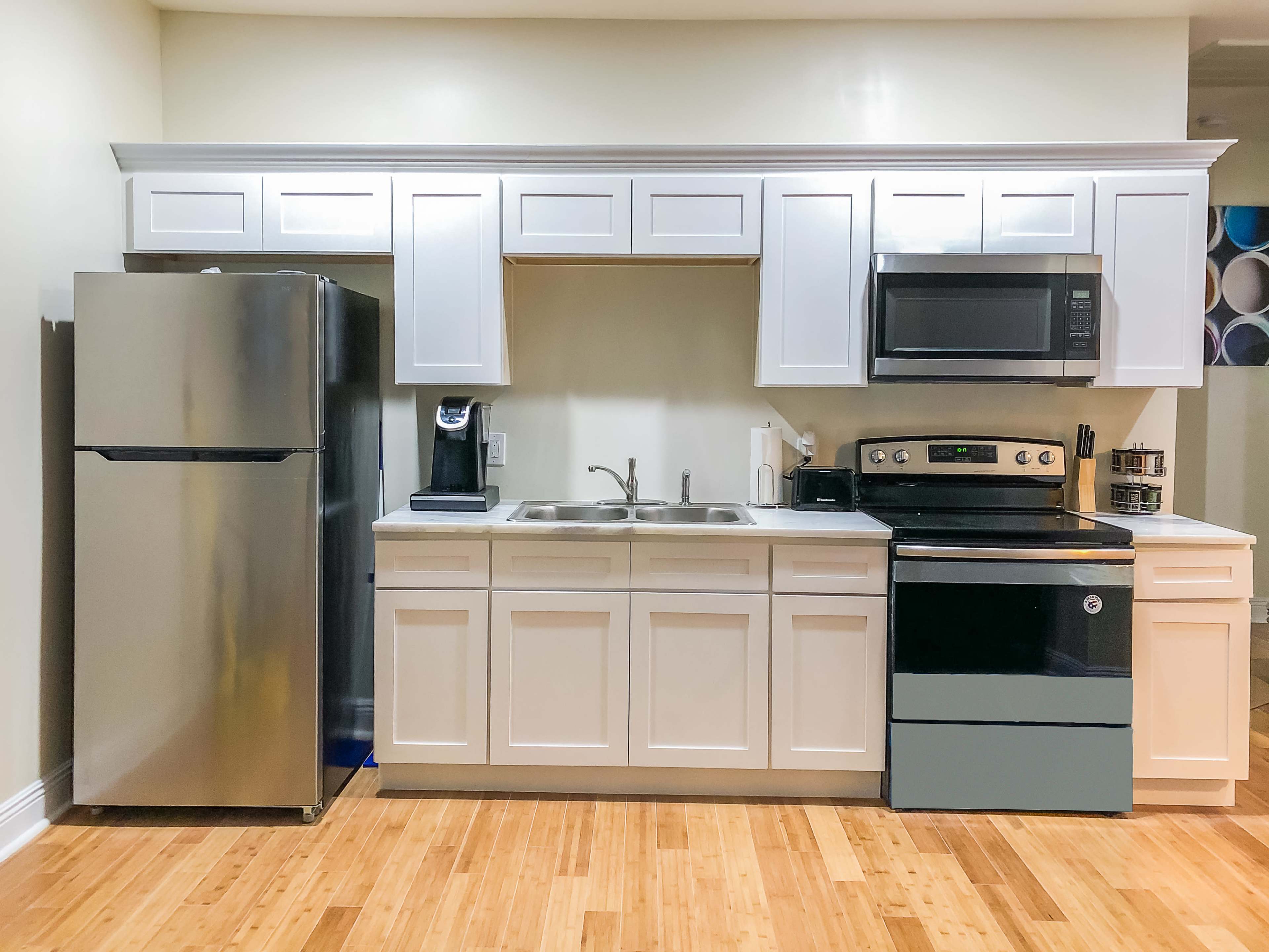 A modern kitchen featuring stainless steel appliances, white cabinetry, and a bamboo floor.