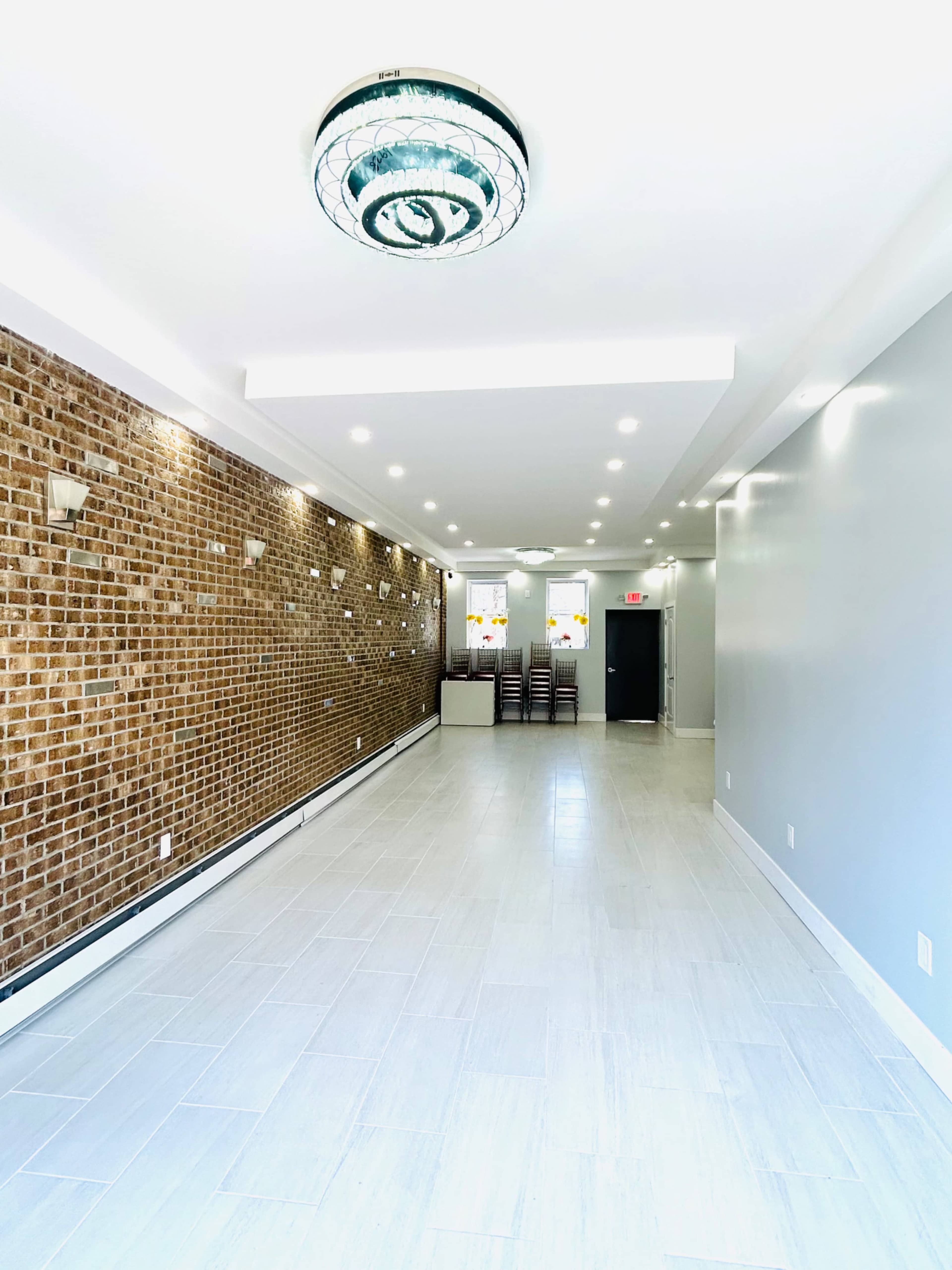 A spacious, modern interior with a brick accent wall, tile flooring, and a reception area at the far end.