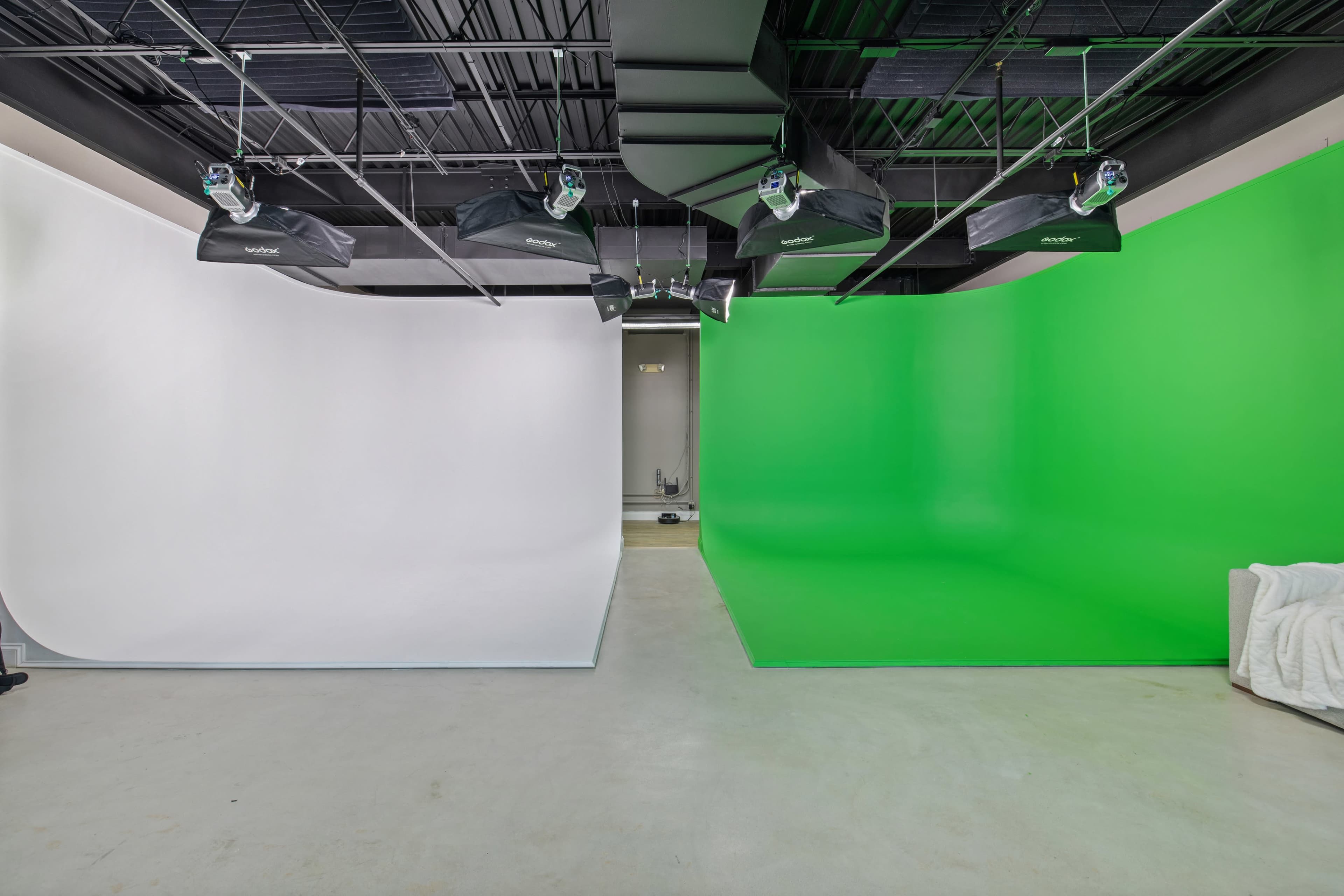 A photography studio with a large white backdrop on one side and a green screen backdrop on the other.