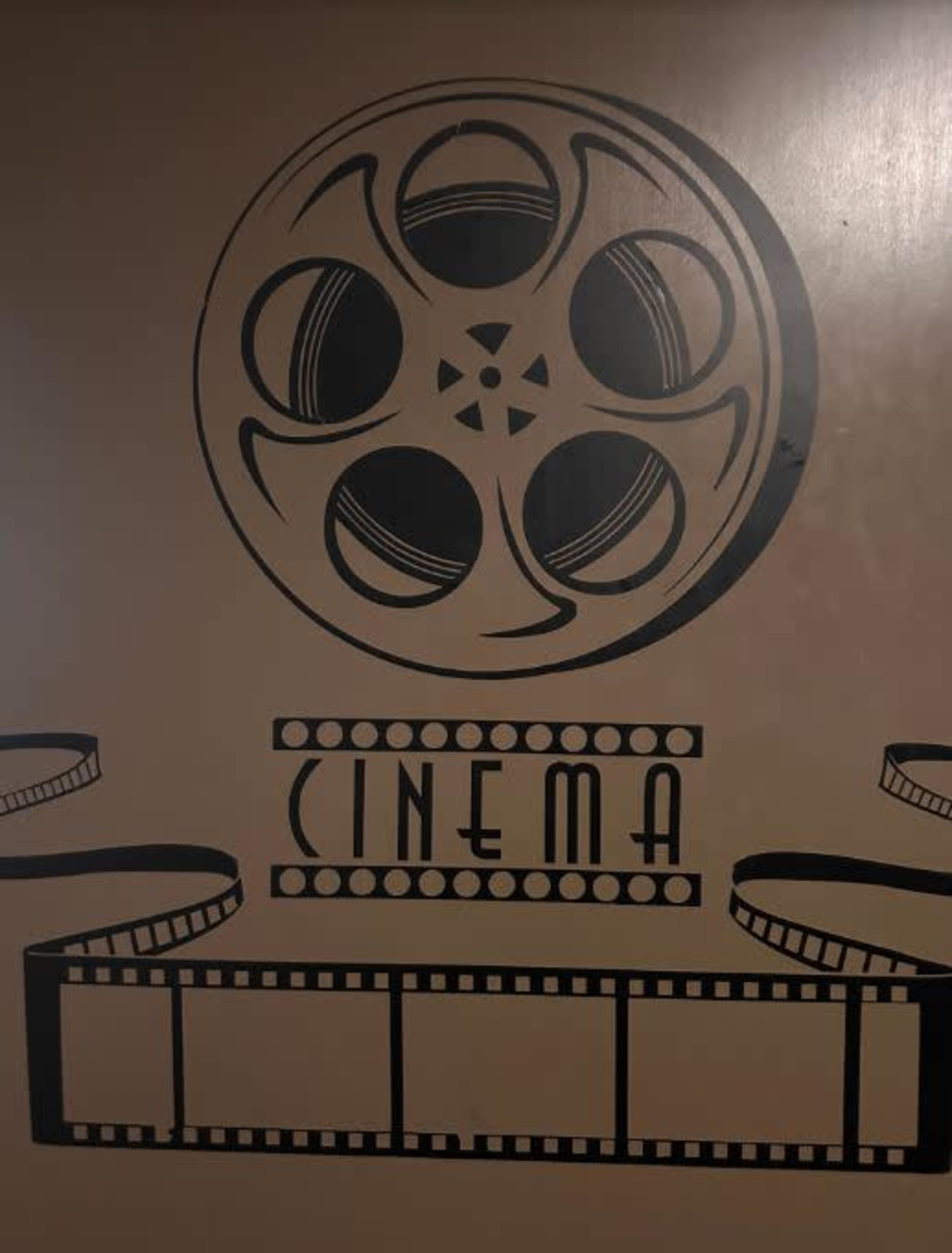 A decorative wall featuring a large film reel and film strip graphic with the word "CINEMA" prominently displayed.