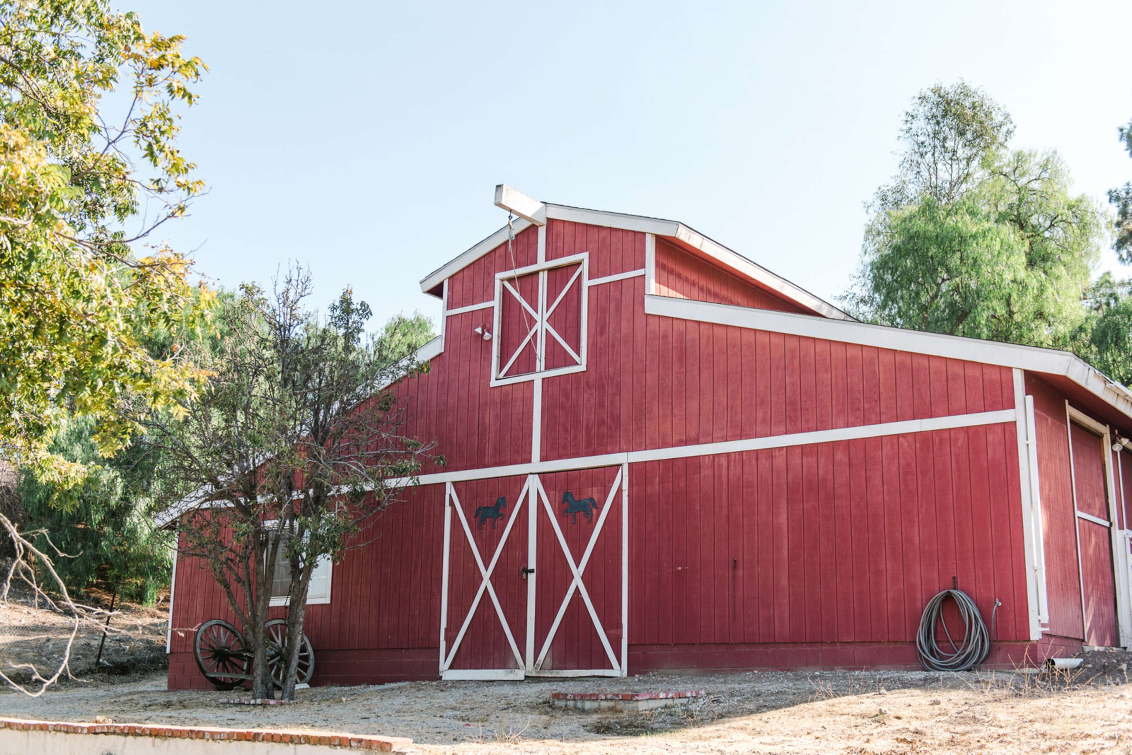 A red barn with white trim set against a backdrop of trees in a rural area.