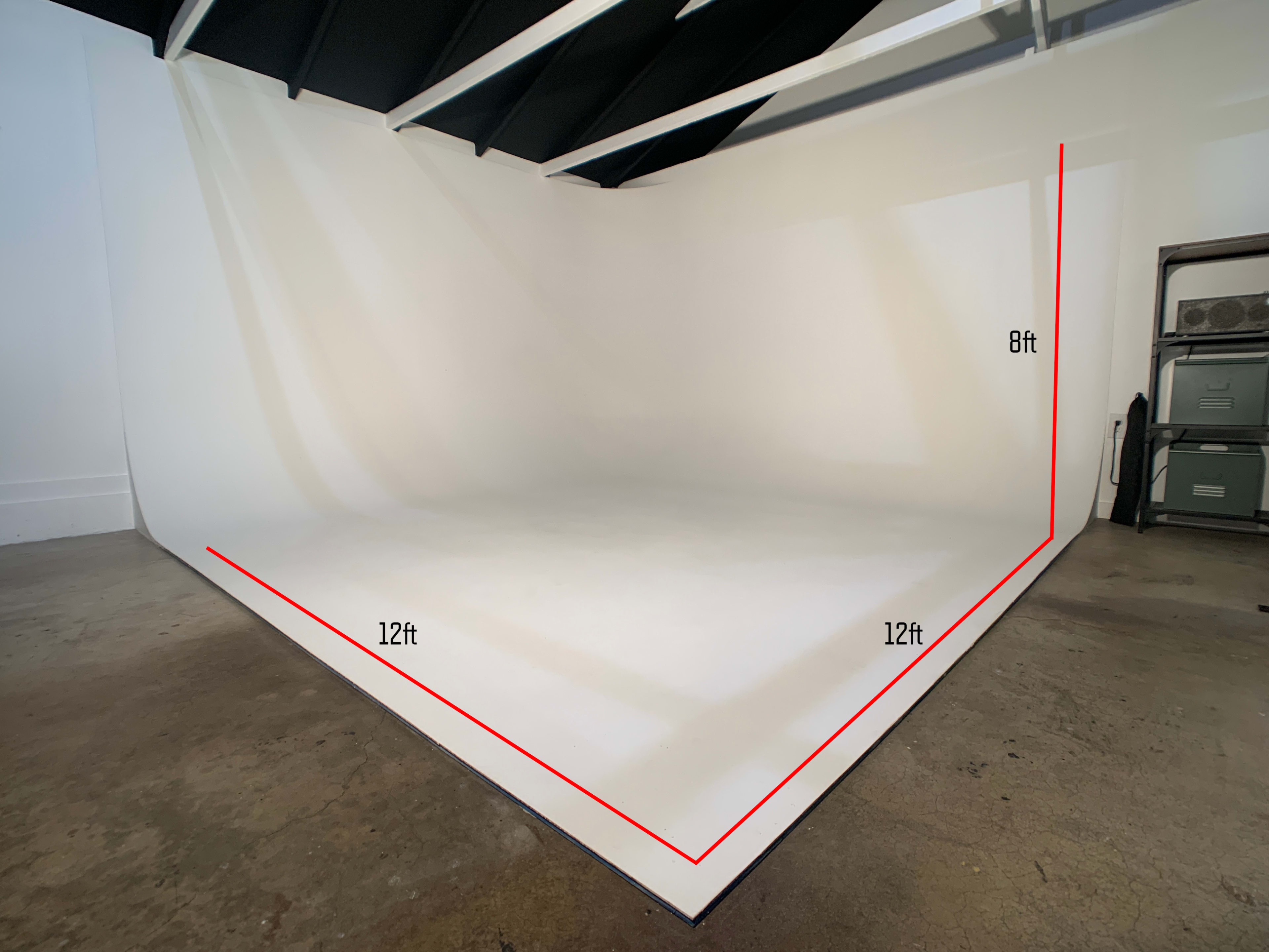 A photography studio with a seamless white backdrop that measures 12 feet on two sides and 8 feet in height.
