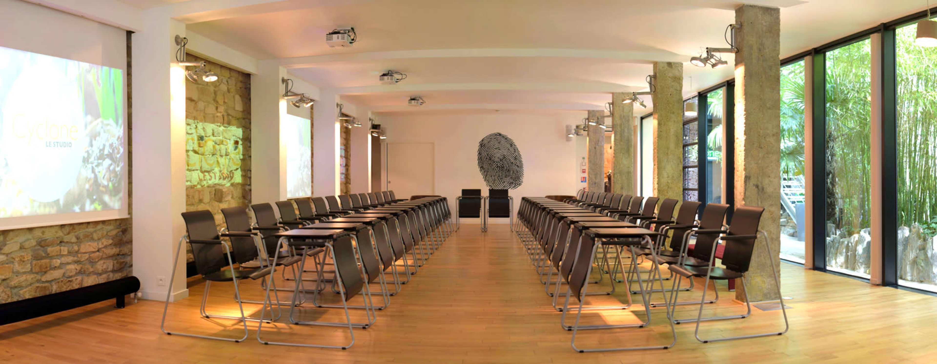 A modern conference room arranged with rows of chairs facing a presentation screen and an artistic fingerprint design on the wall.