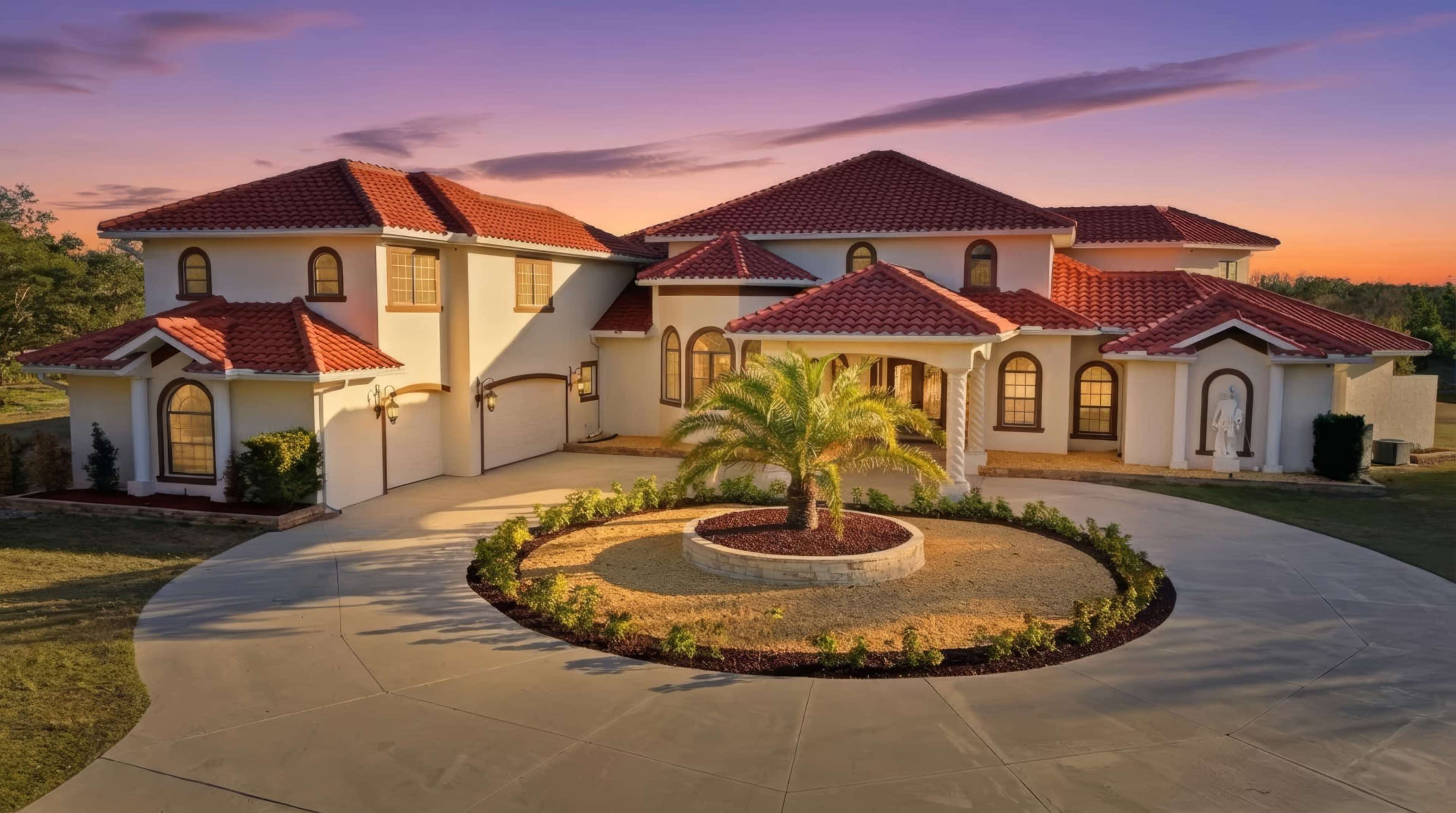 The image shows a large, two-story house with a red tiled roof, palm trees, and a circular driveway leading to a landscaped front yard at sunset.