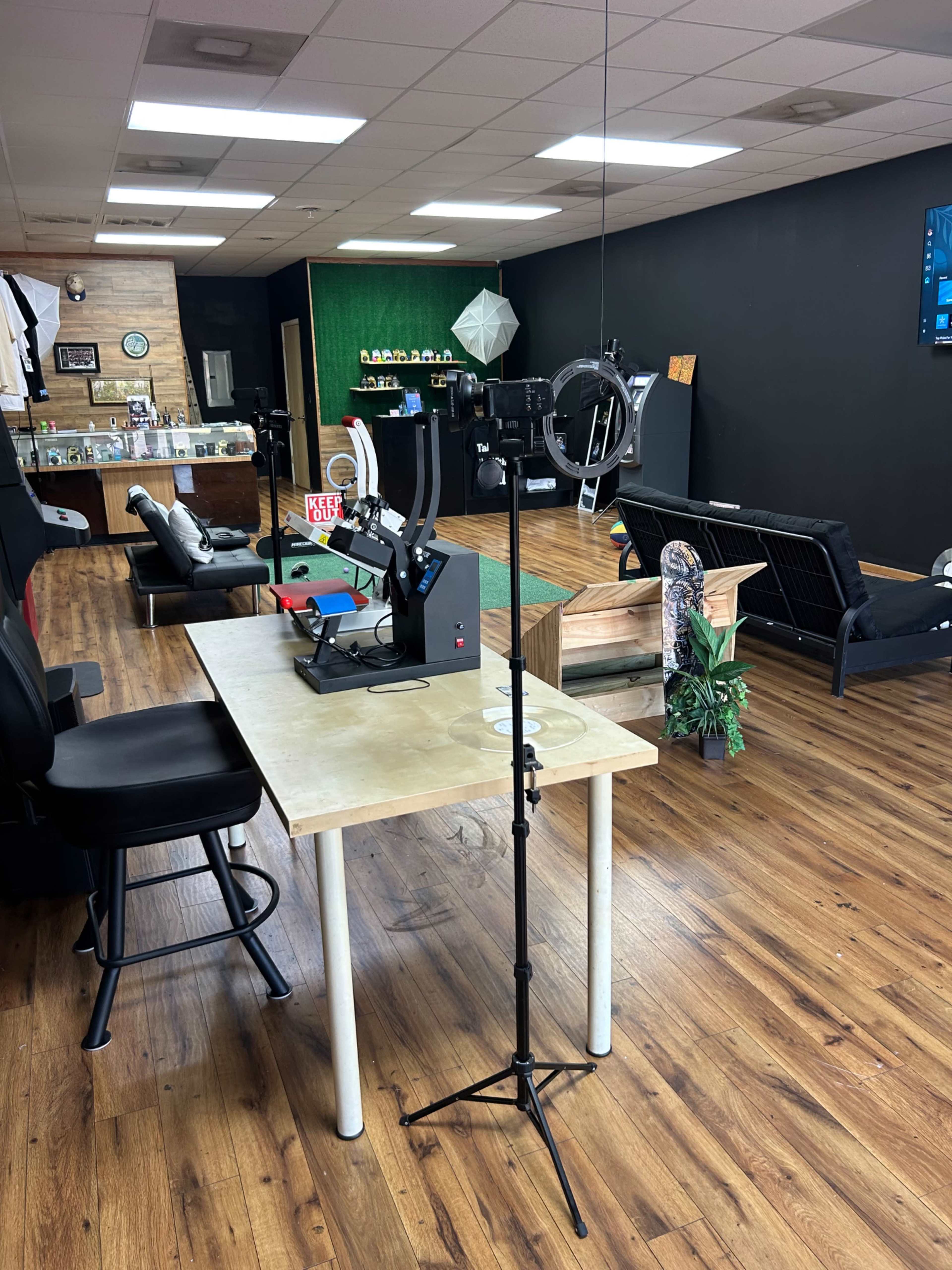 The image shows a room filled with various furniture items, including chairs and a table with equipment used for photography or videography, set against a backdrop of dark walls.