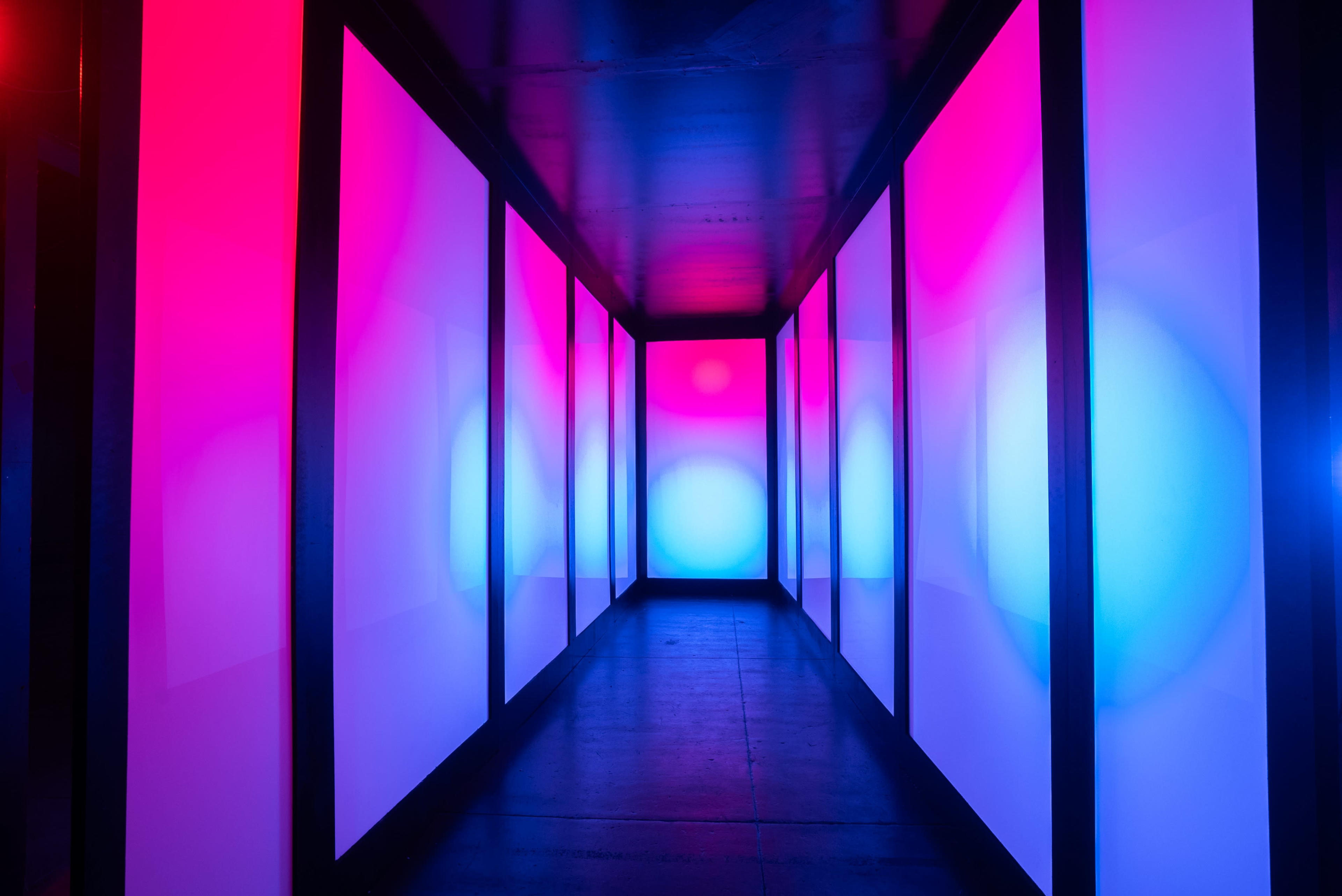 The hallway features walls illuminated in pink and blue lights, creating a vibrant and colorful atmosphere.