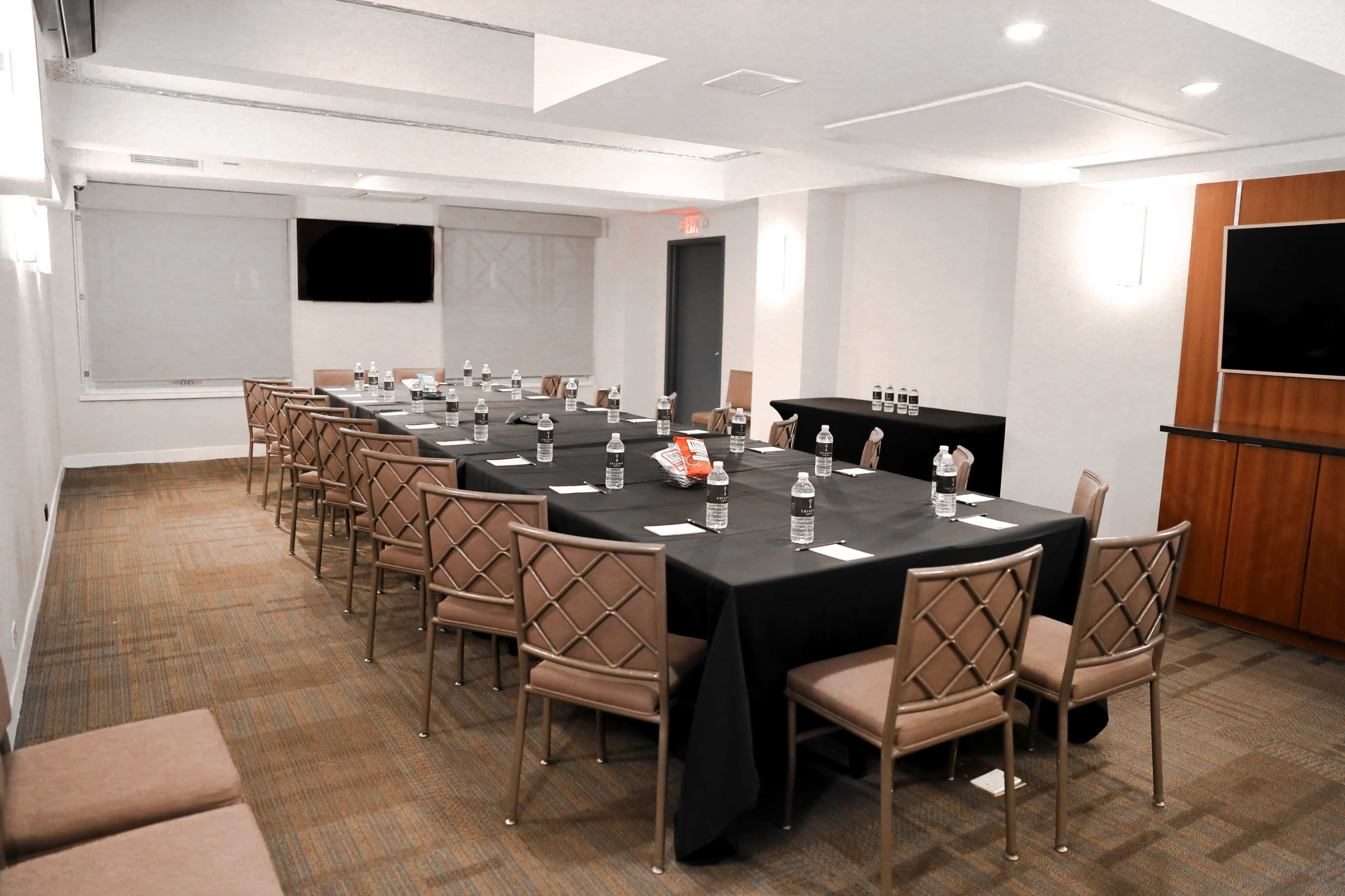 A long conference table is set with water bottles and snacks in a well-lit meeting room.