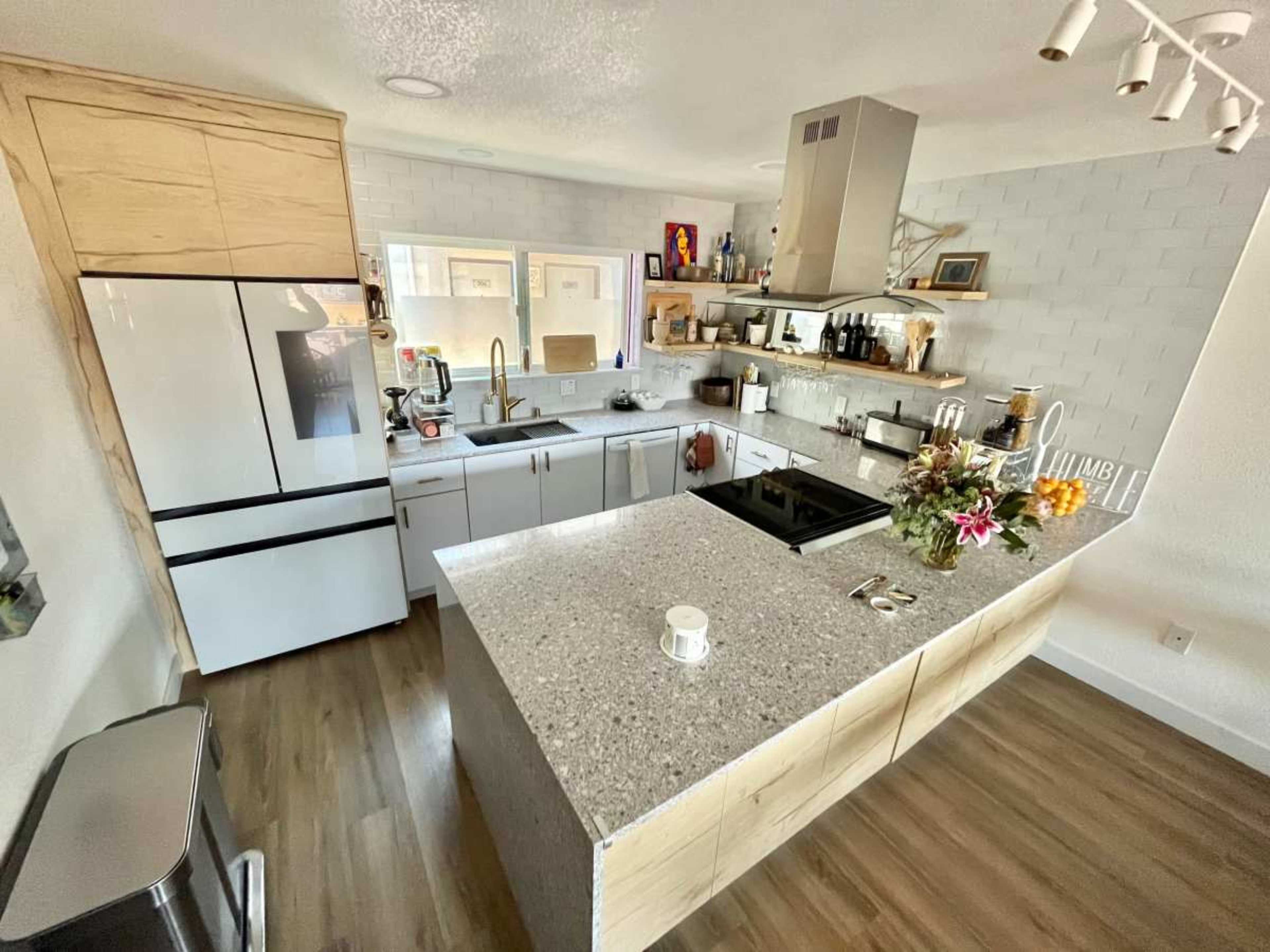 A modern kitchen with a central island, stainless steel appliances, and wooden cabinetry.