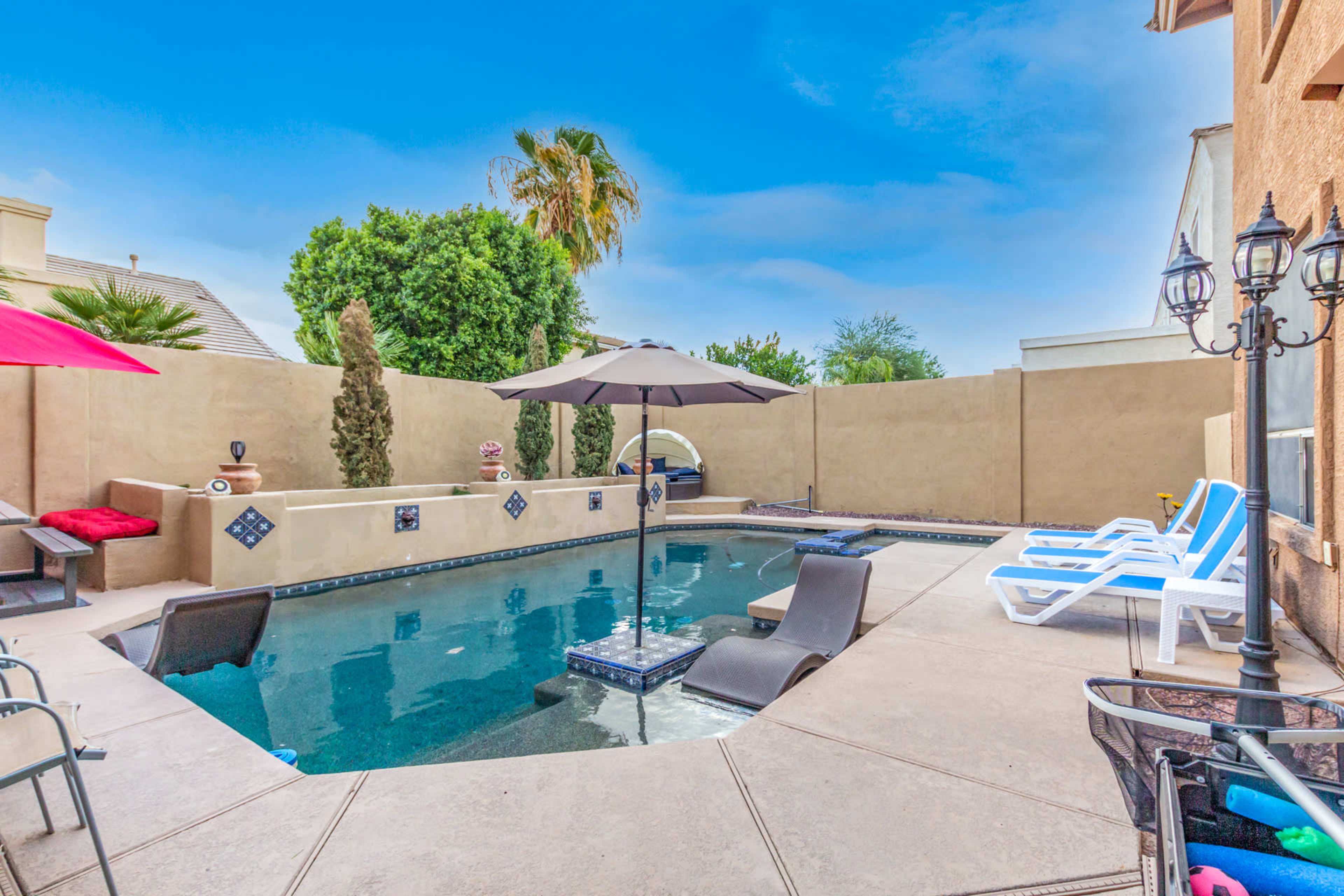 The image shows a backyard pool area with an umbrella, lounge chairs, and a surrounding wall.