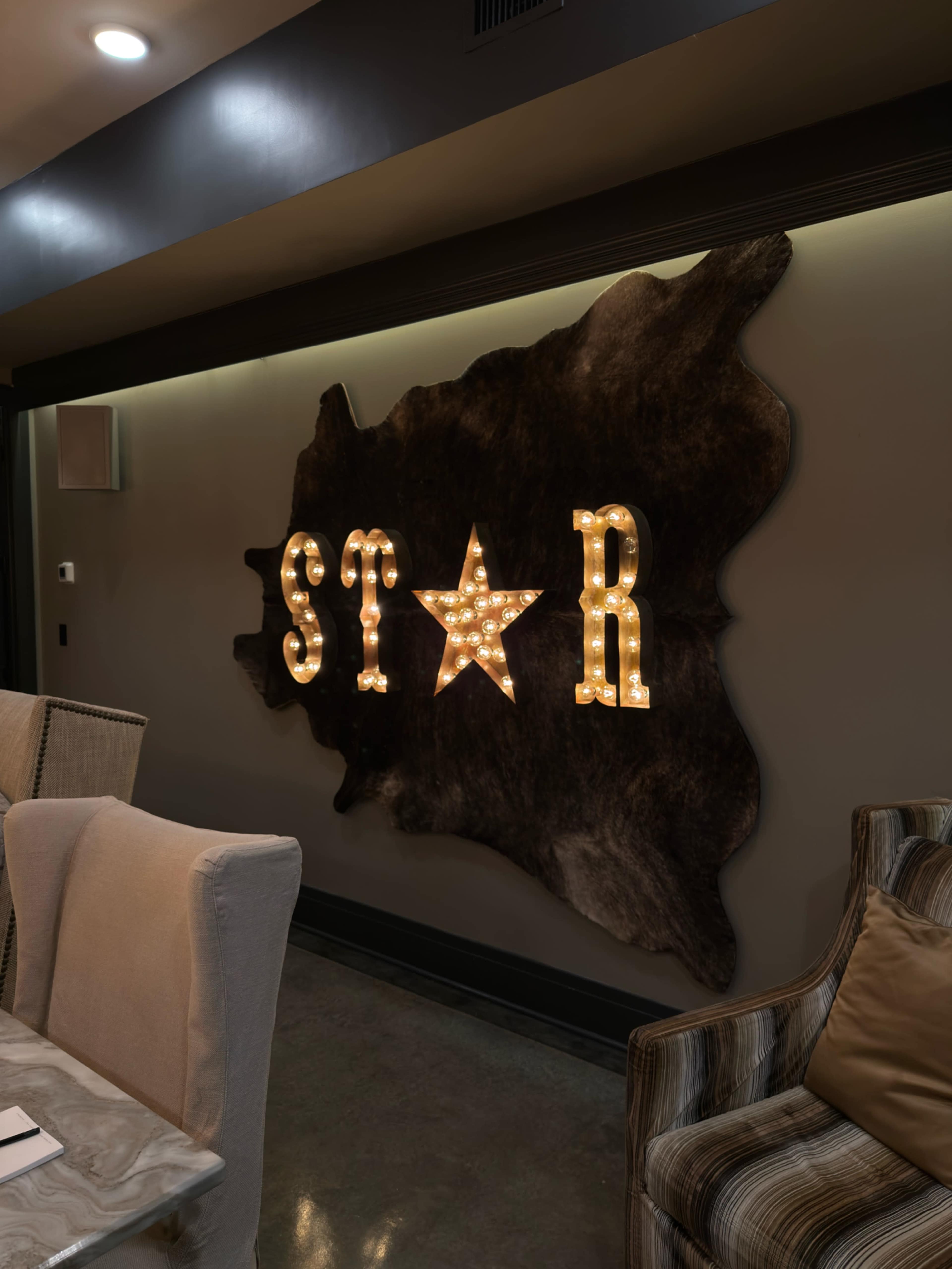 The image shows a decorative wall display featuring the illuminated letters "S T A R" alongside a star on a textured backdrop.