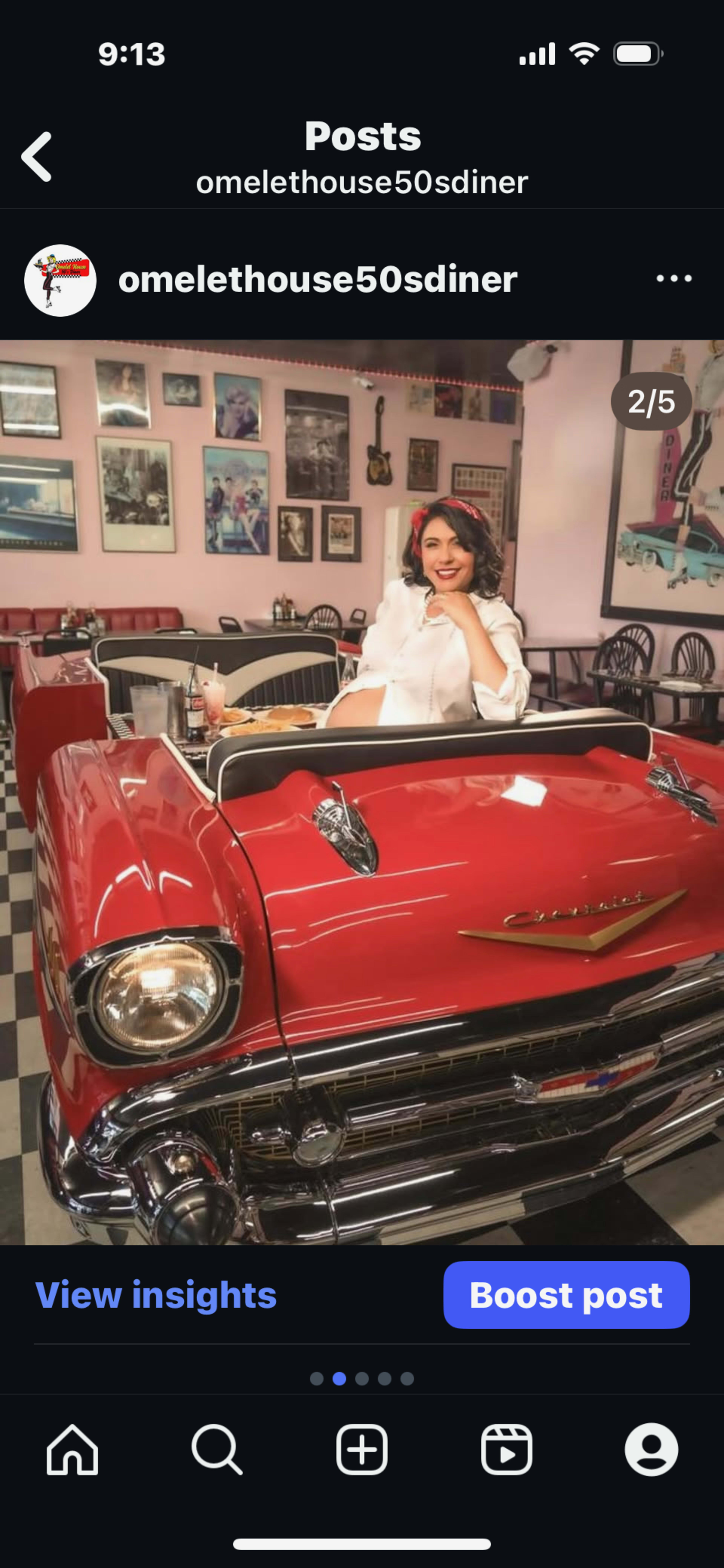 A woman seated in a vintage red convertible inside a 1950s diner, with retro decor and checkered floors in the background.