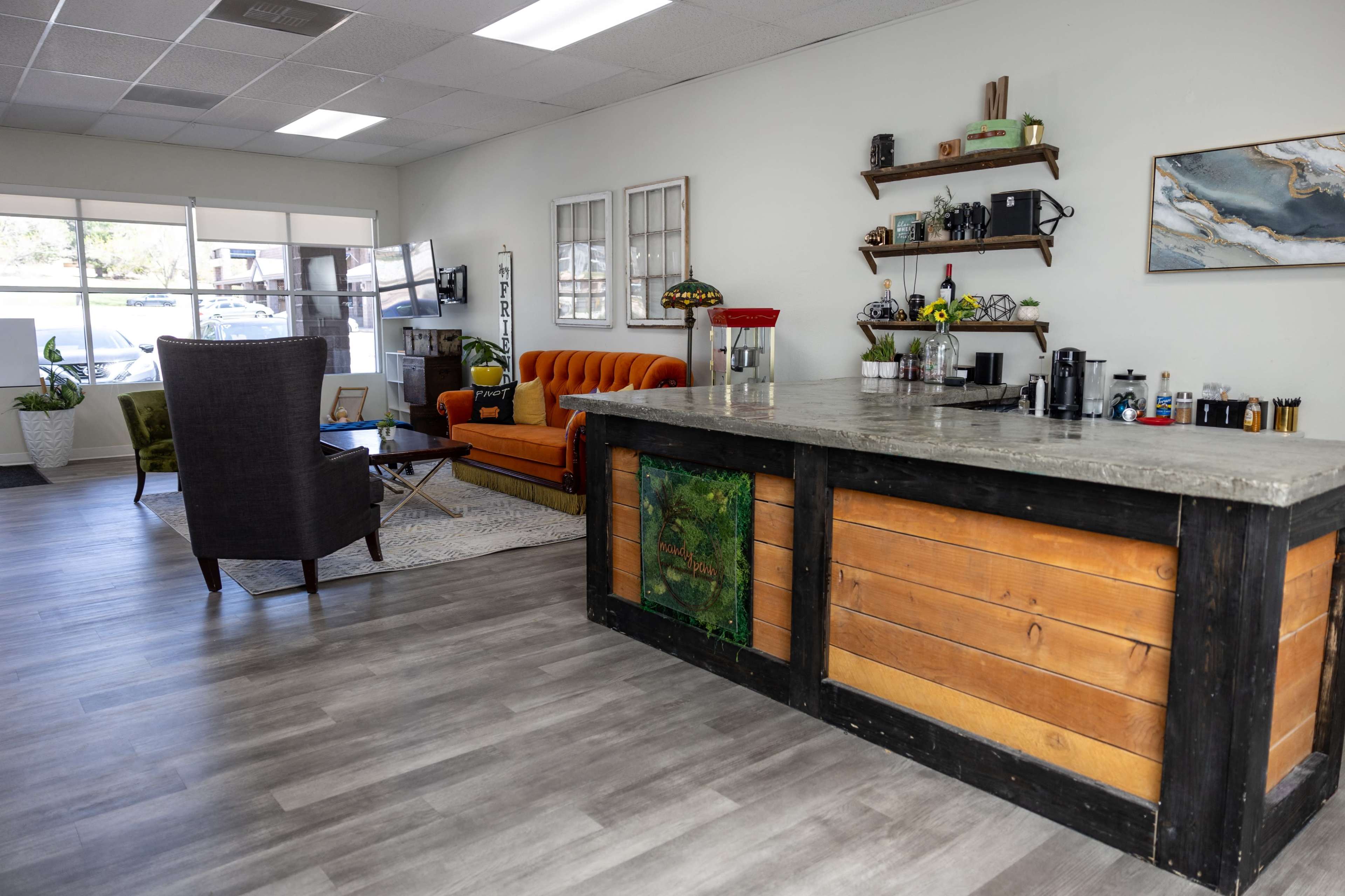A modern interior of a cozy café or lounge with a concrete counter, an orange couch, and a seating area.
