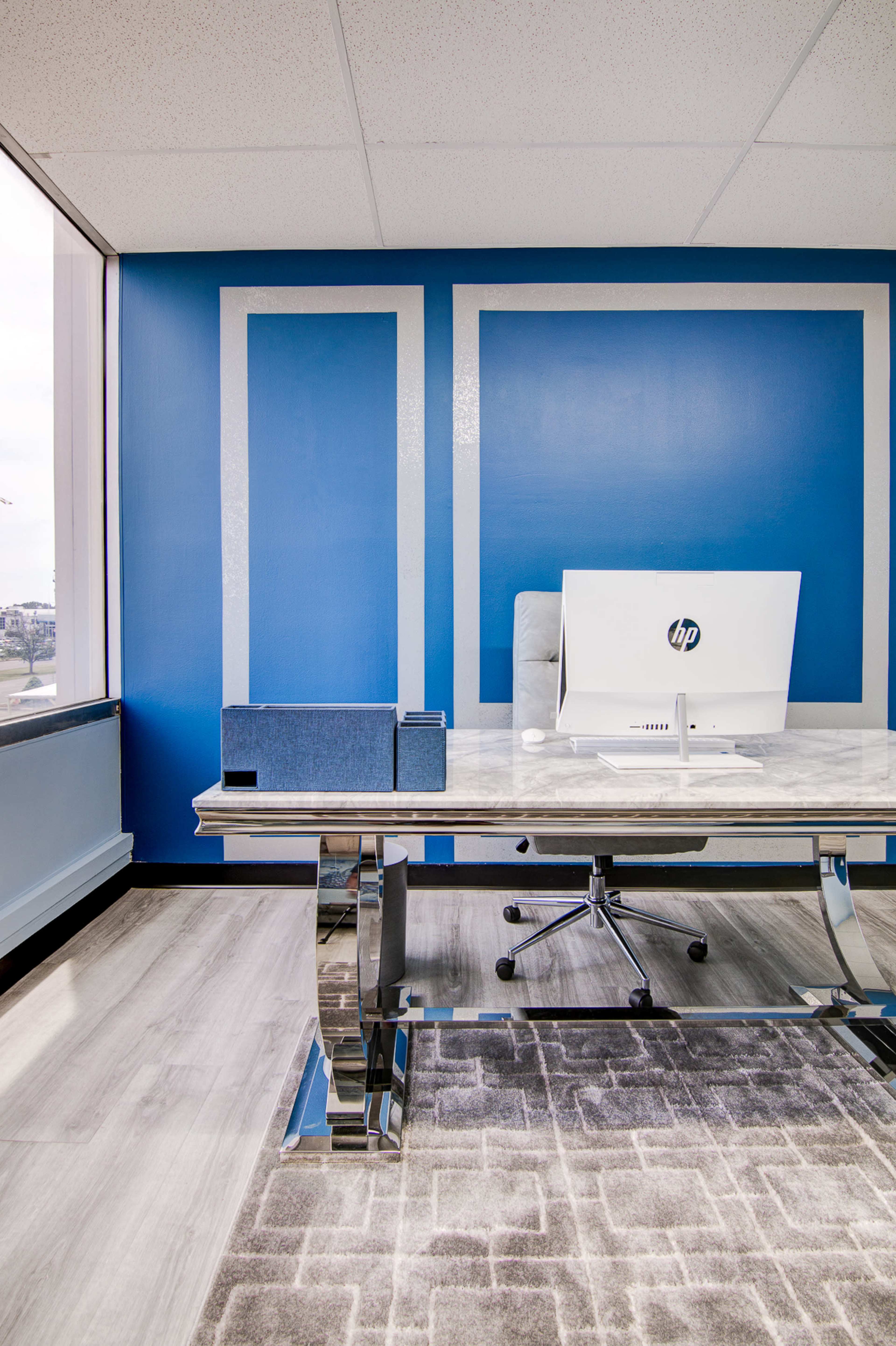 The image shows a modern office space with a marble desk, an HP computer, and blue accent walls.
