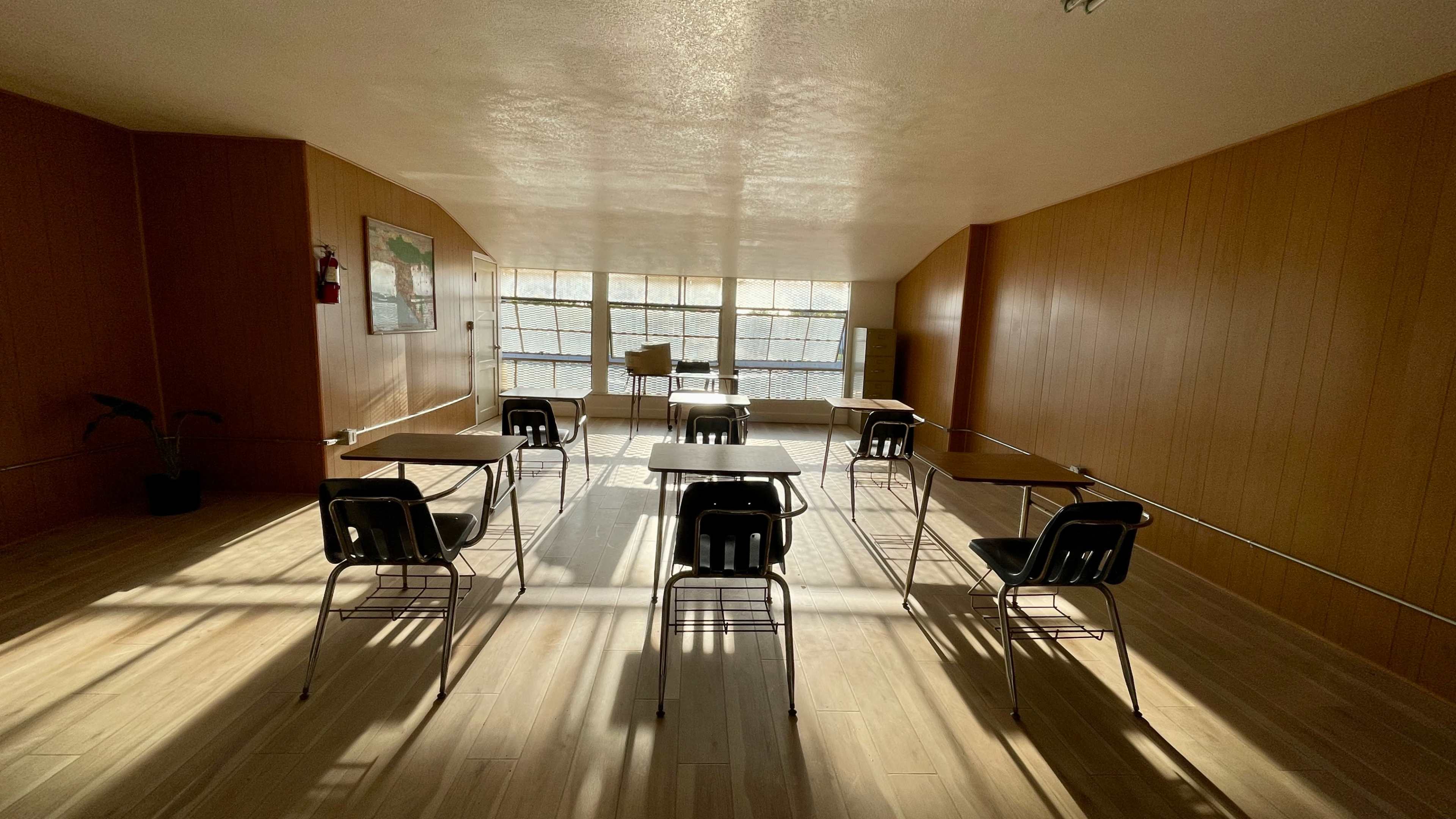 An empty classroom with several desks and chairs arranged in a spacious, well-lit area.