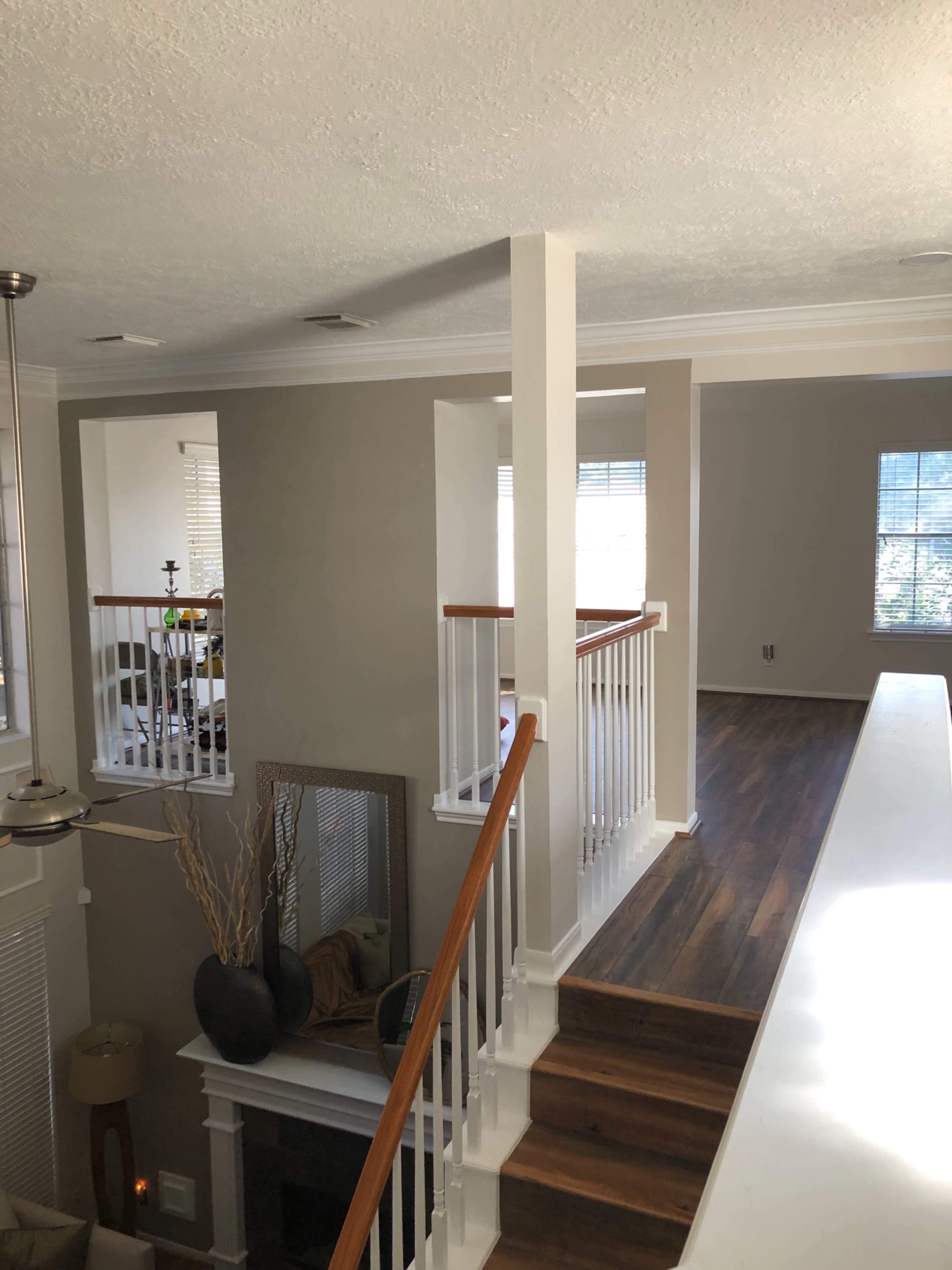 A modern interior of a two-story home with a staircase leading to an upper level and natural light streaming through windows.