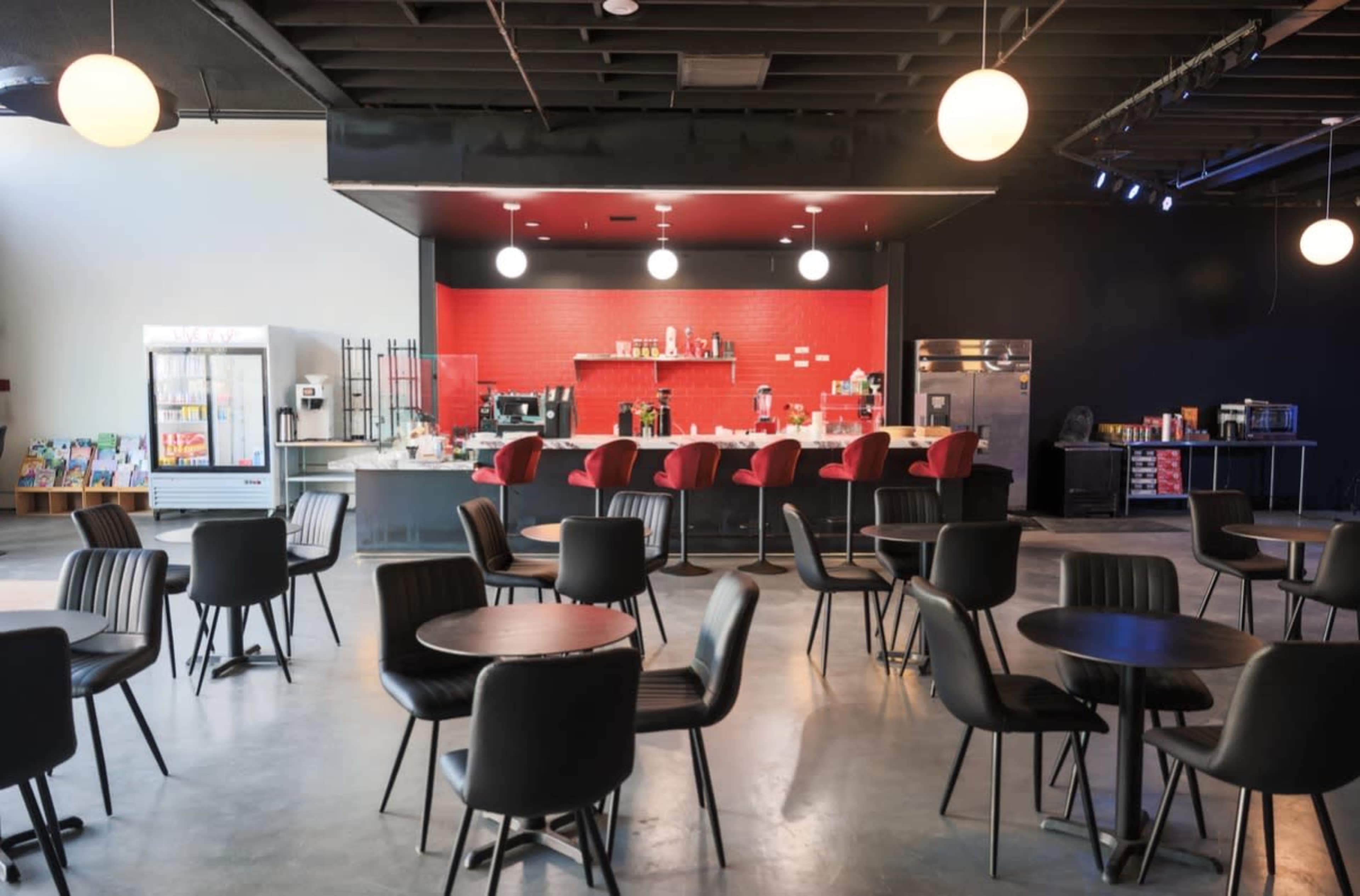The image shows a modern café space with black tables and red-accented counter seating, illuminated by round pendant lights.