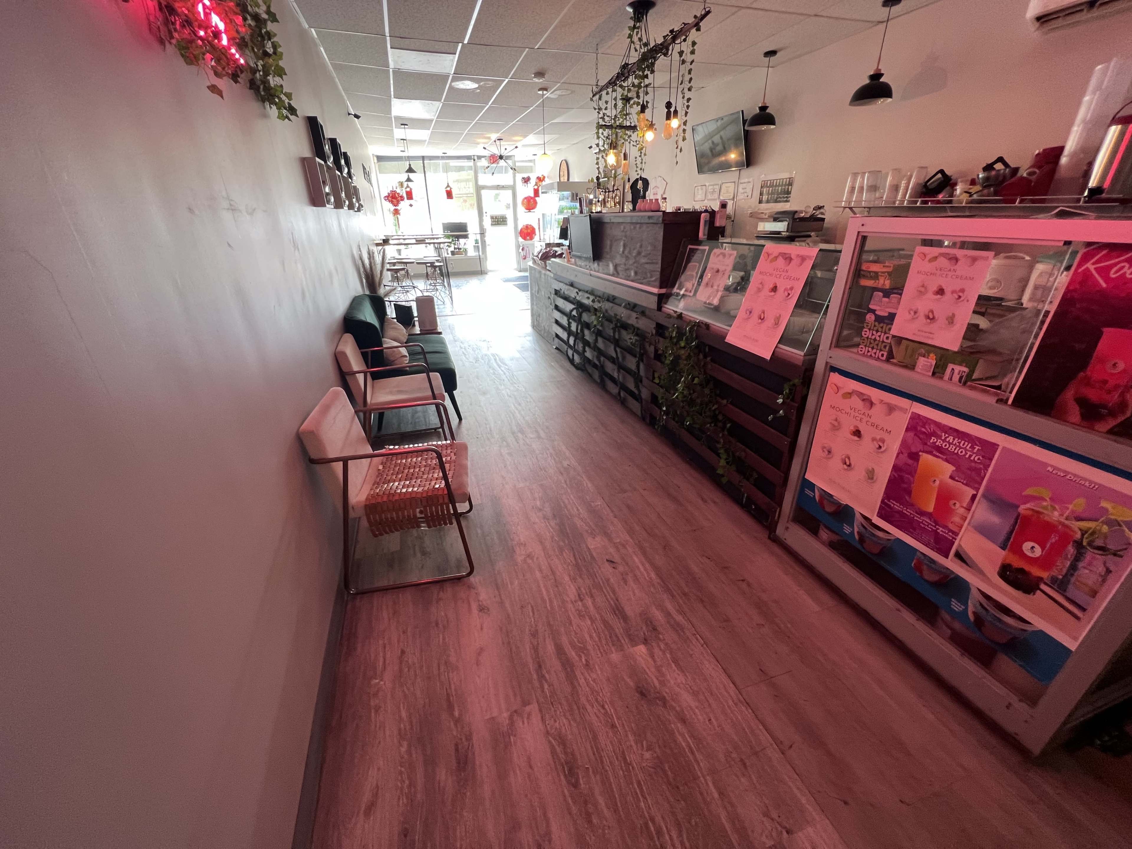 A narrow corridor of a cafe with seating on one side and display counters on the other.