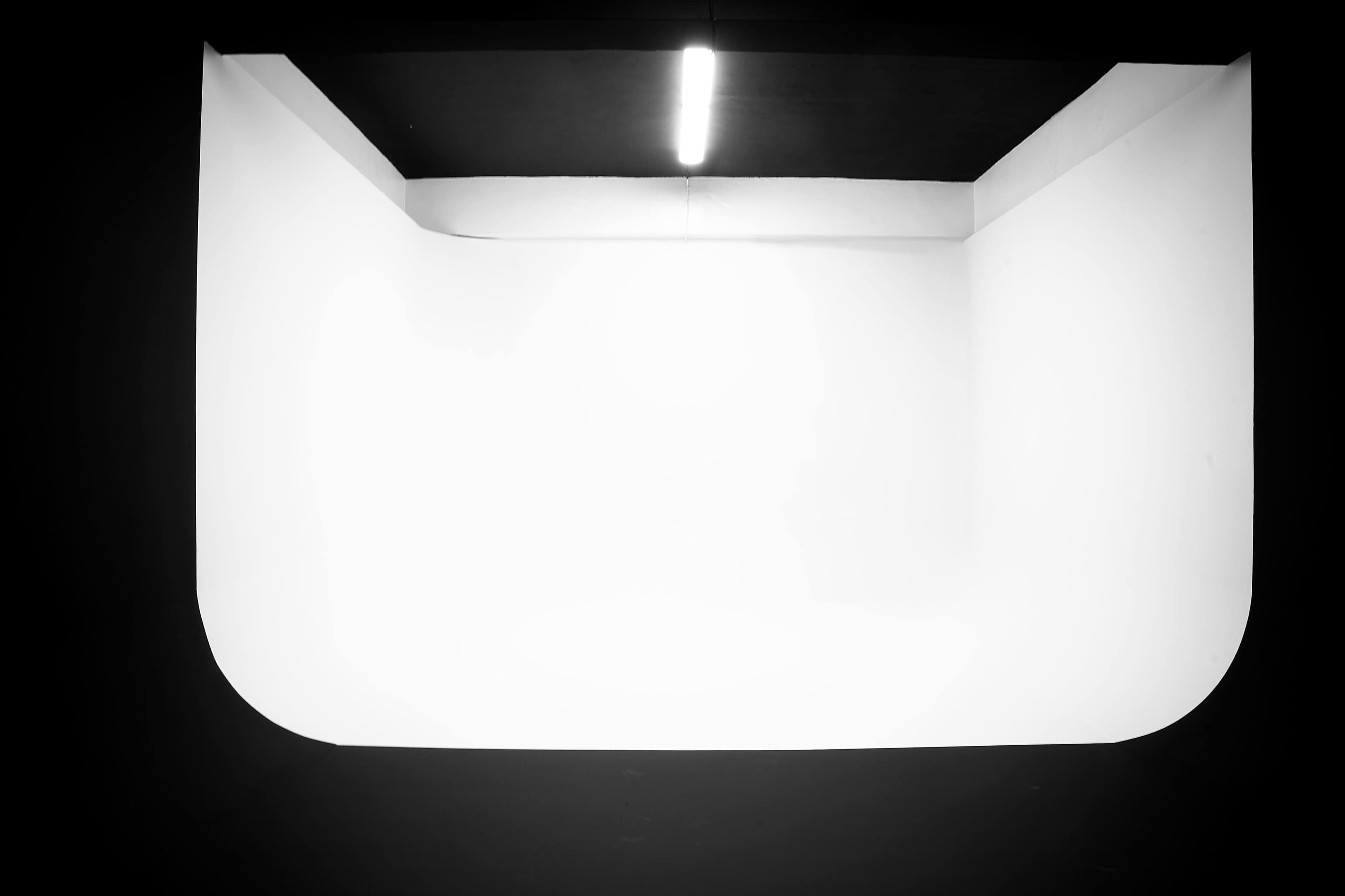 The image shows a minimalist, well-lit room with curved edges and a predominantly white wall.
