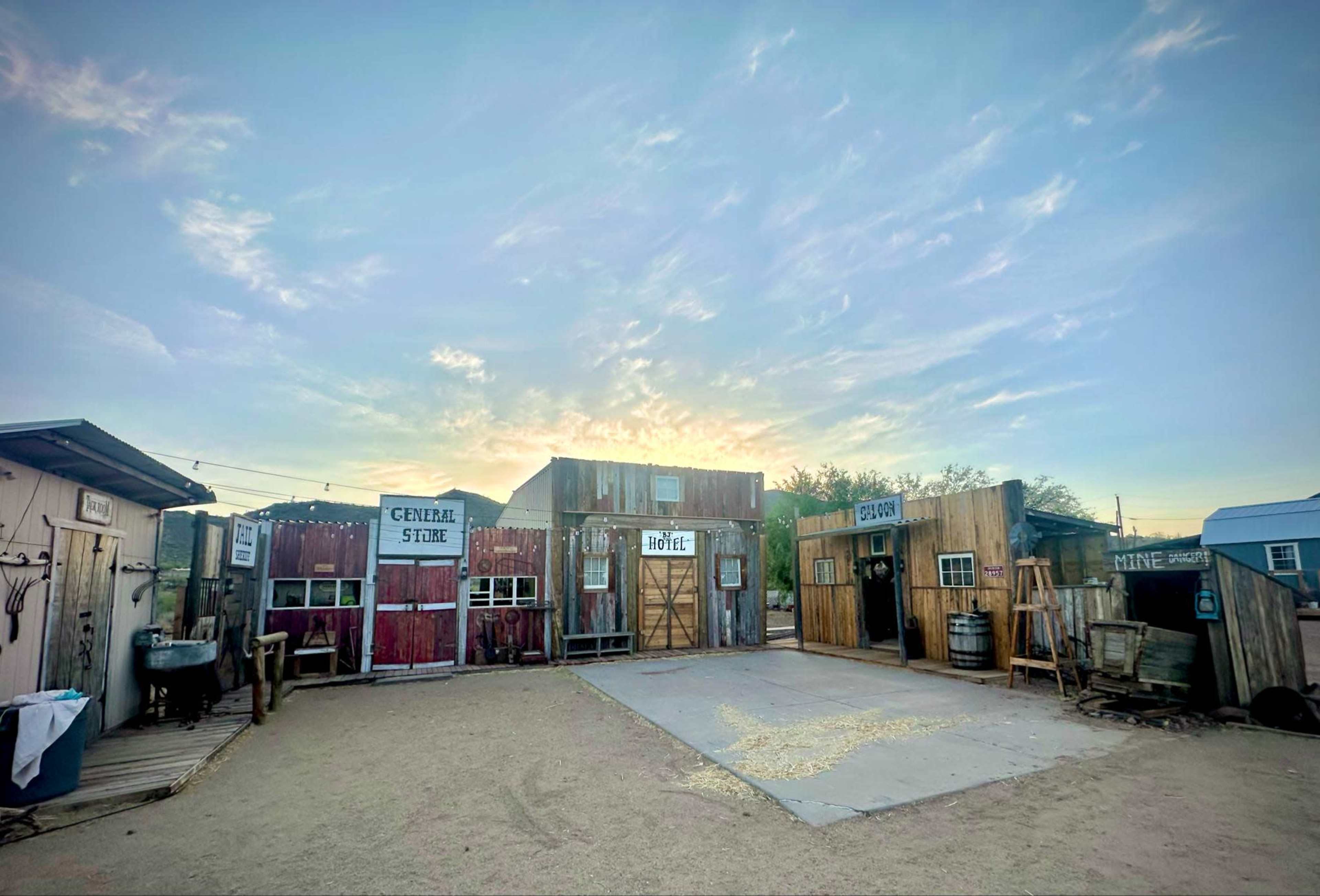 The image shows a western-style ghost town with several wooden buildings labeled "General Store," "Hotel," and "Saloon" under a bright sky.