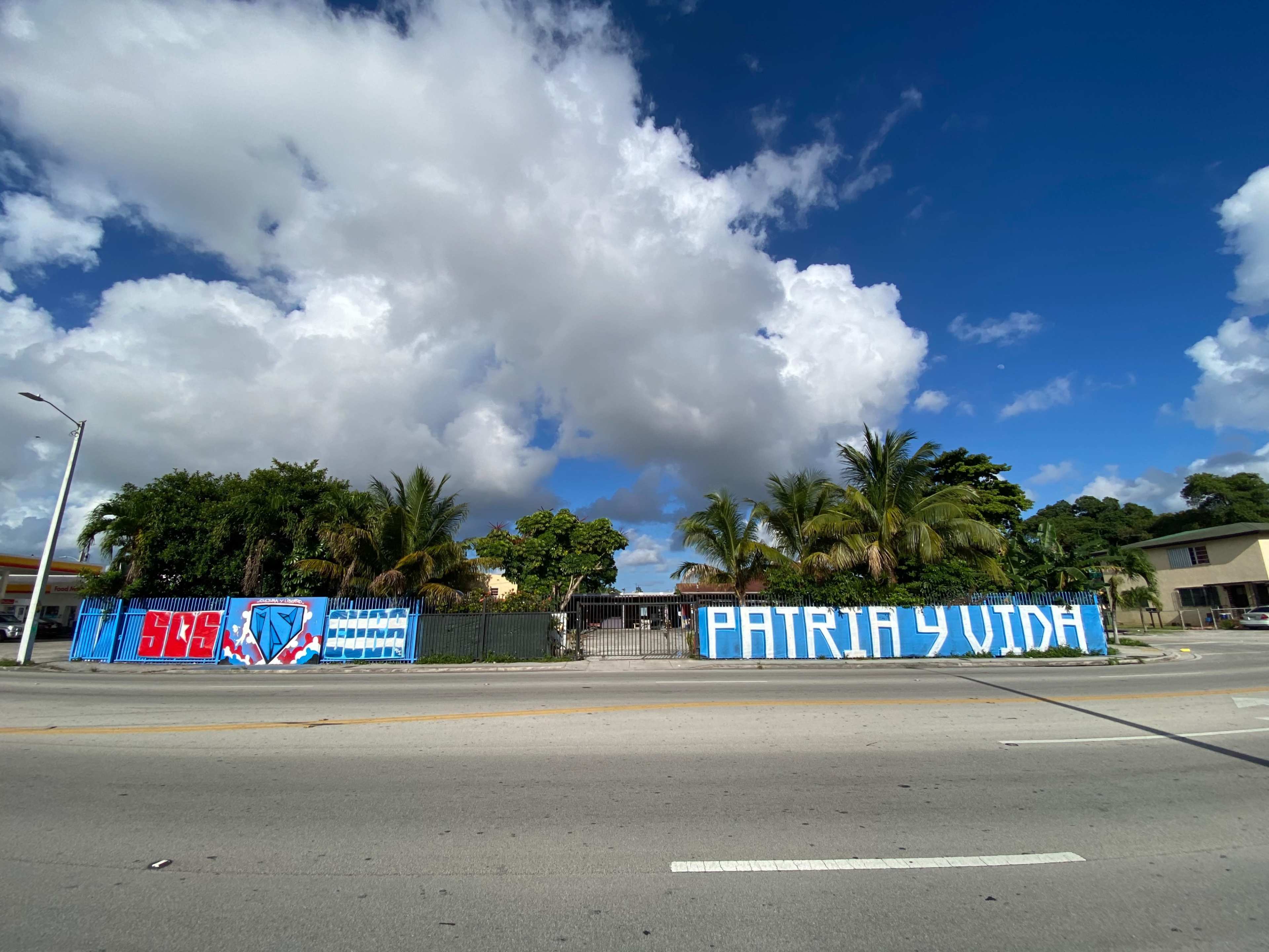 A building surrounded by palm trees with large blue and white murals displaying the phrases "SBS" and "PATRIA Y VIDA" on the walls.