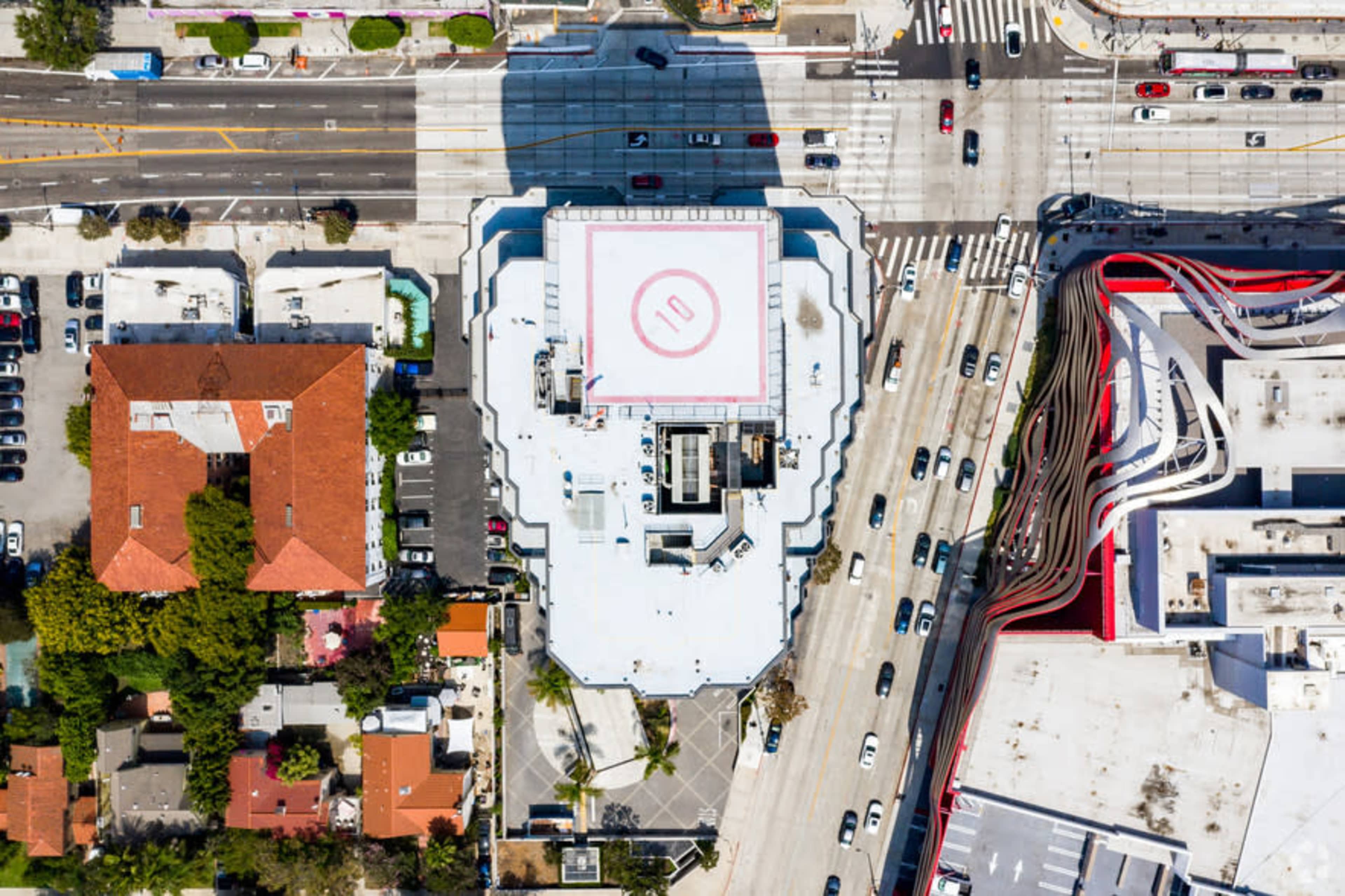 The image shows an aerial view of a large building with a circular red number "10" marking on its flat roof, surrounded by streets and smaller buildings.