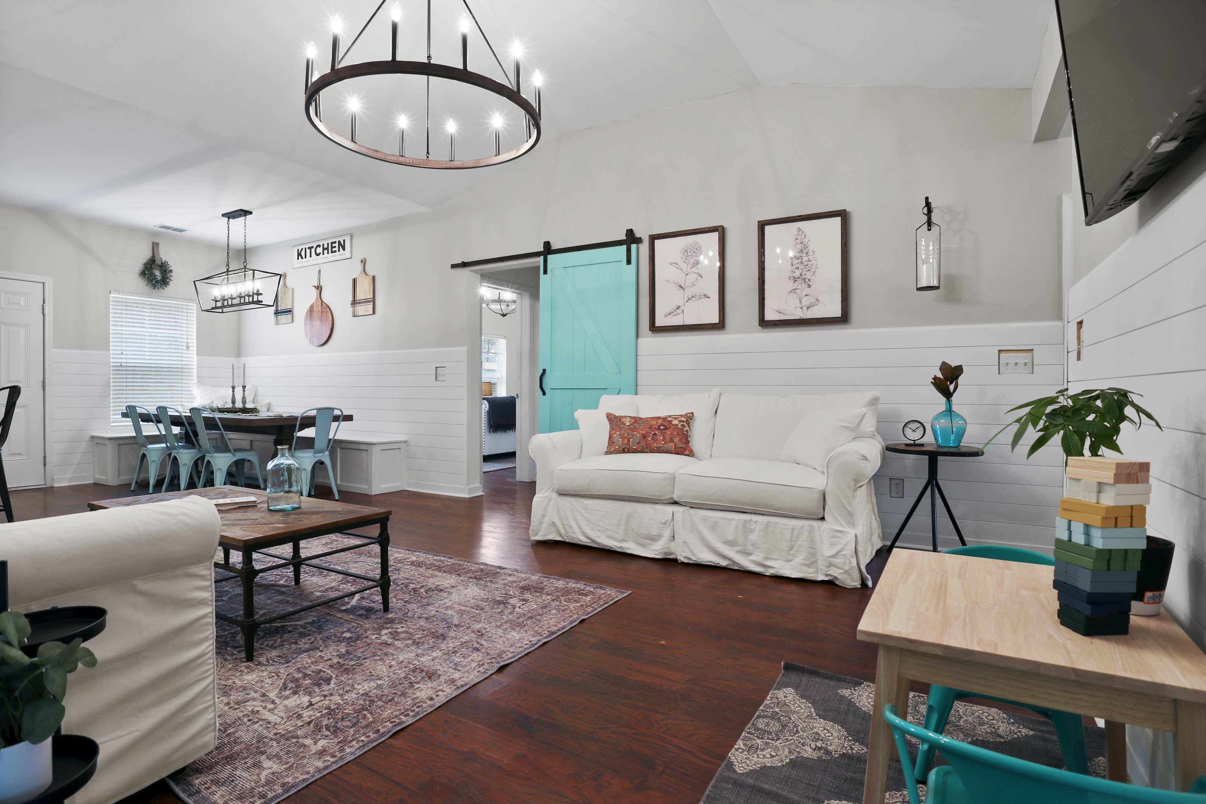 The living room features a white sofa, a wooden coffee table, and a sliding barn door leading to the kitchen.