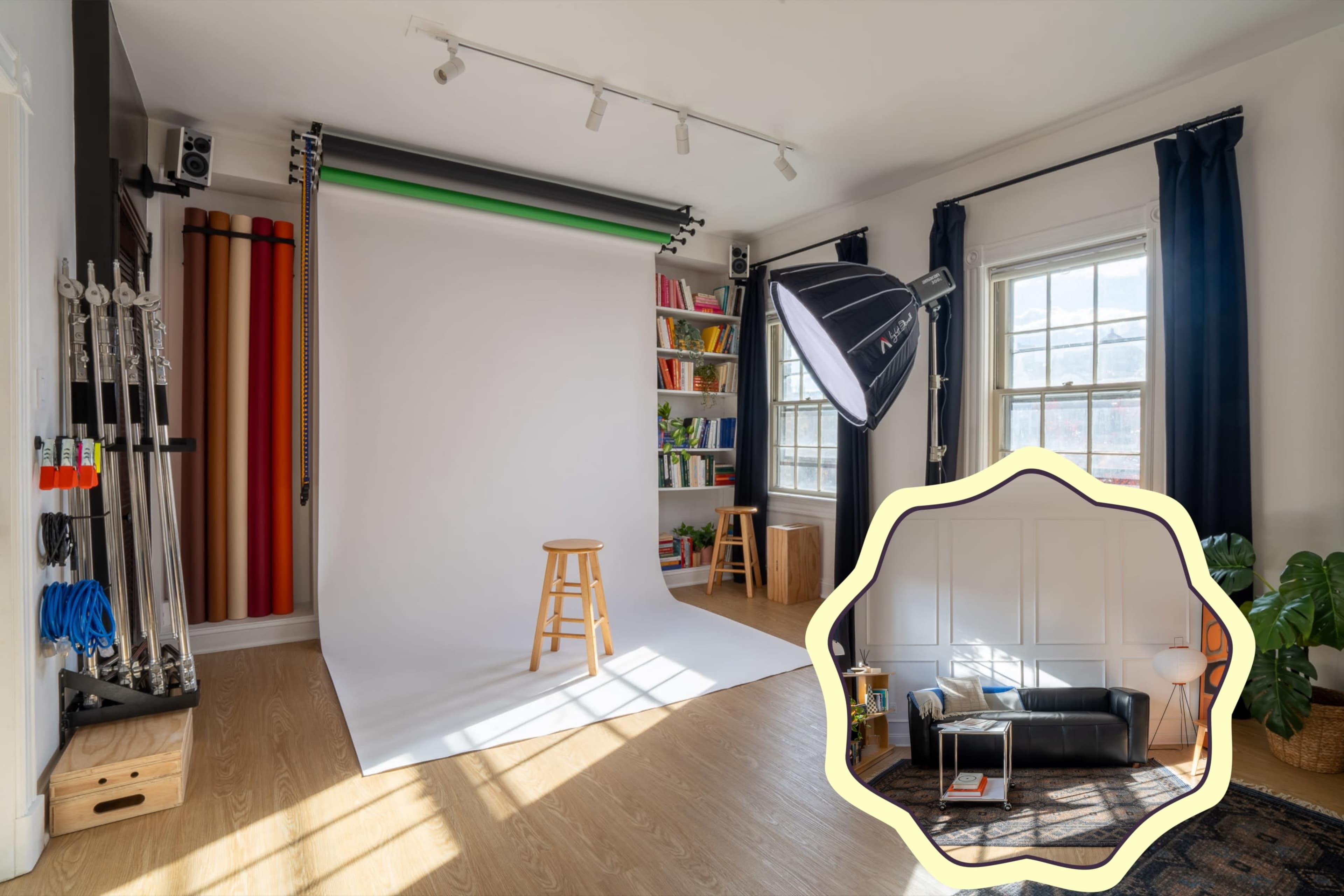 The image shows a photography studio with a white backdrop, a wooden stool, a light source, and a corner featuring a black leather couch and a decorative rug.