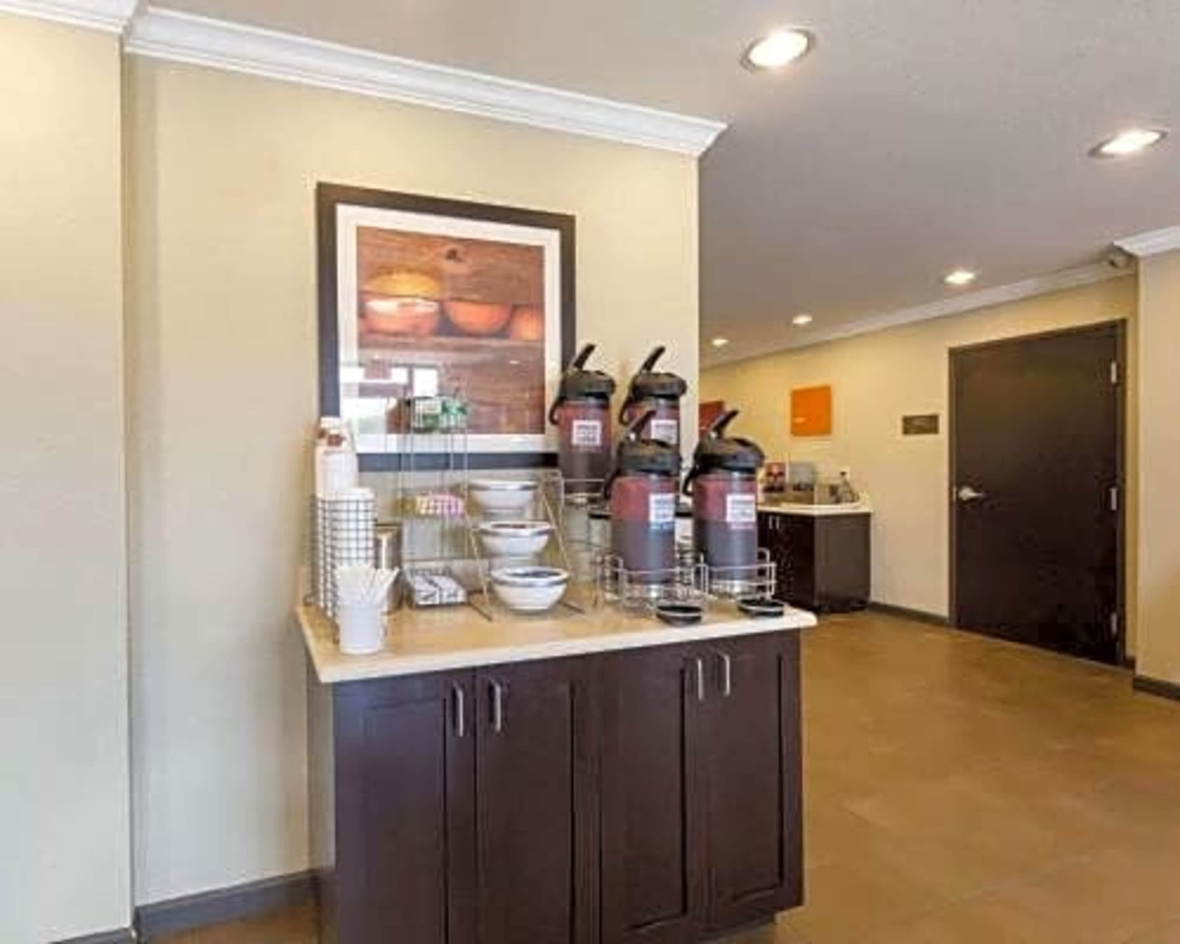 A coffee station with several coffee dispensers and bowls is set up on a counter in a brightly lit room.